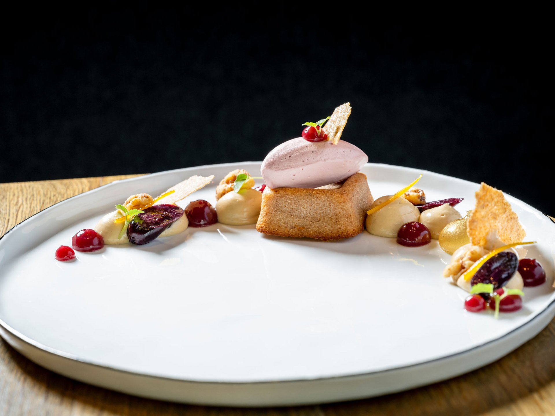 Seezeitlodge : Galerie photos Dessert élégant avec biscuit, glace et sauces fruitées sur assiette blanche