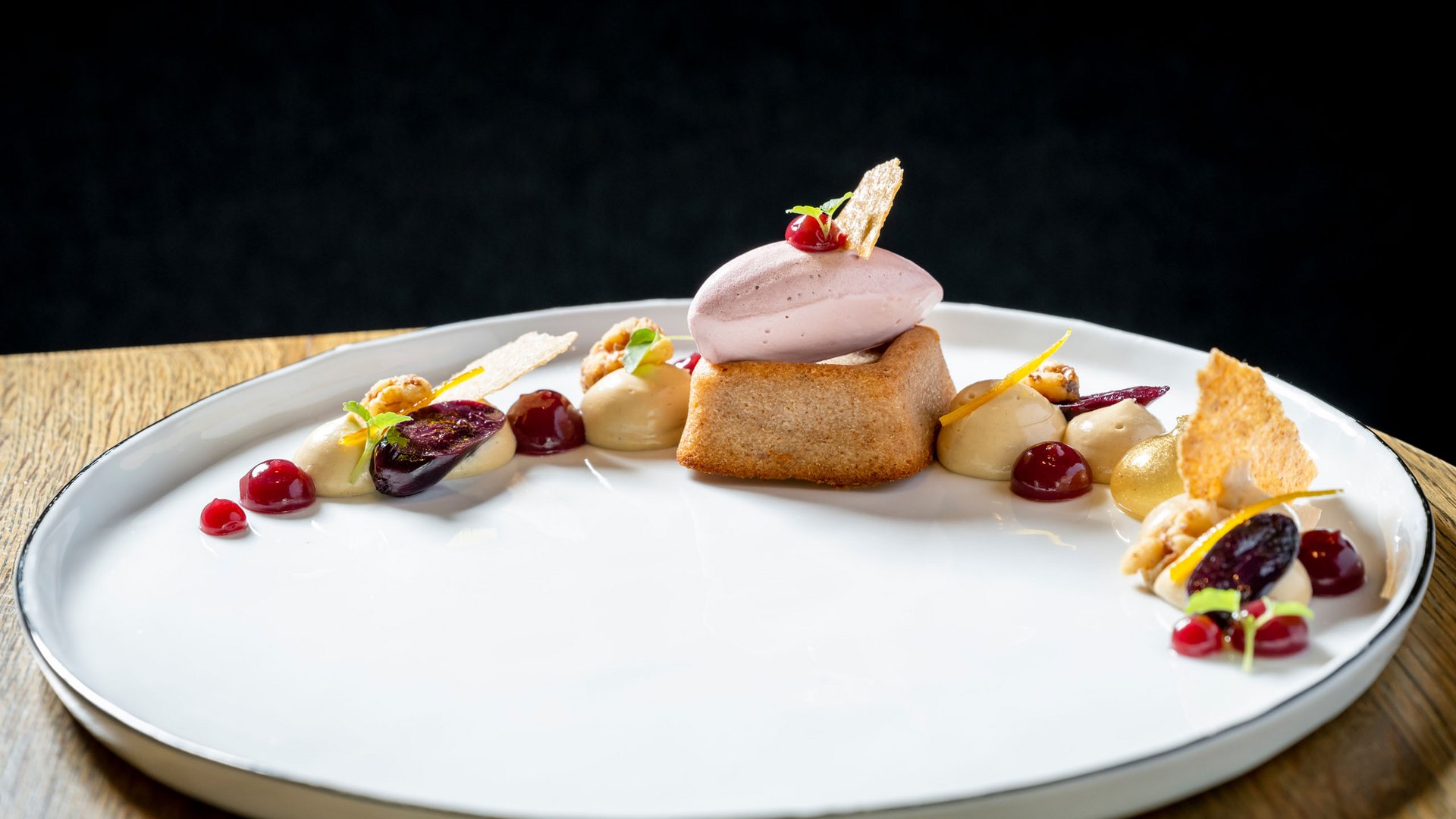 Seezeitlodge : Galerie photos Dessert élégant avec biscuit, glace et sauces fruitées sur assiette blanche