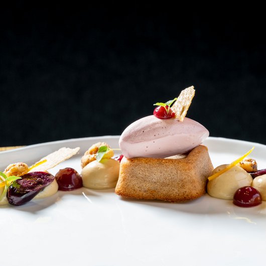 Ihr Genusshotel am Bostalsee Elegantes Dessert mit Biskuit, Eis und Fruchtsoßen auf weißem Teller