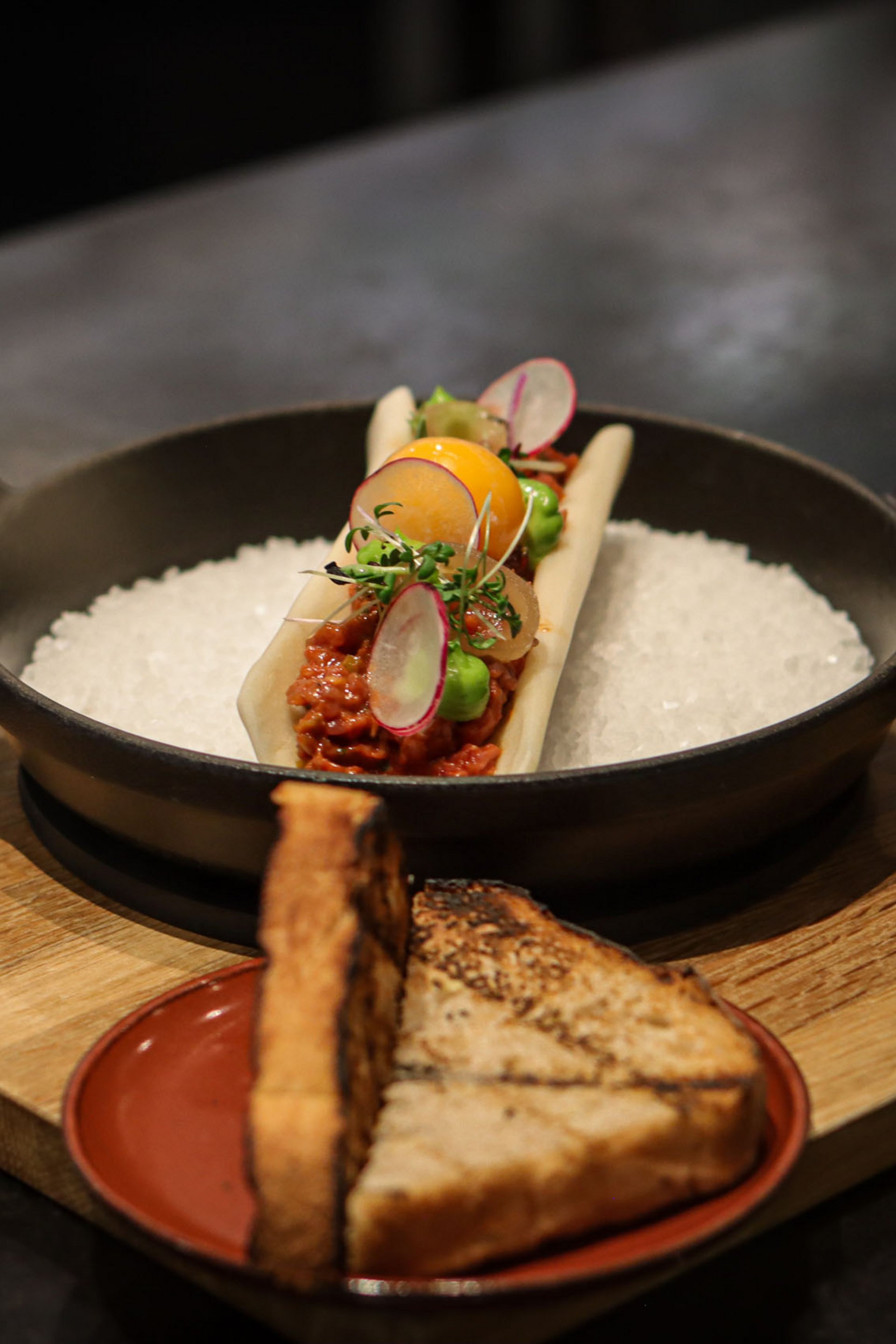 Seezeitlodge: Bildergalerie Fein garniertes Gericht mit Toastbrot auf Holzbrettern serviert