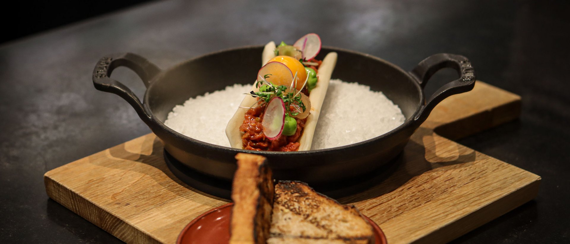 Seezeitlodge: Bildergalerie Fein garniertes Gericht mit Toastbrot auf Holzbrettern serviert