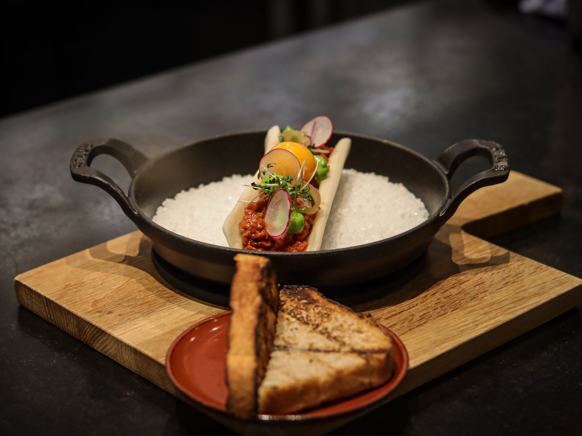 Seezeitlodge: Bildergalerie Fein garniertes Gericht mit Toastbrot auf Holzbrettern serviert