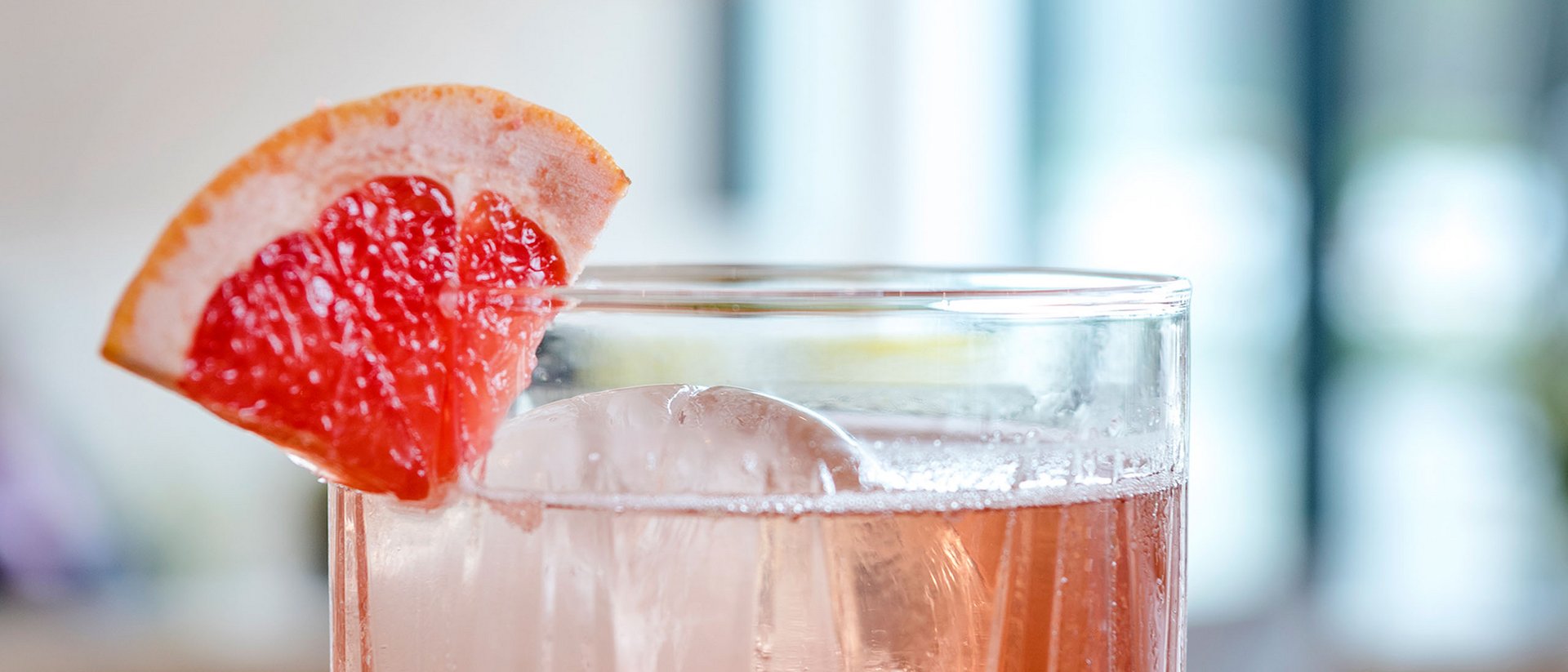 Seezeitlodge: Bildergalerie Cocktail mit Eis und Grapefruitecke auf Holzoberfläche