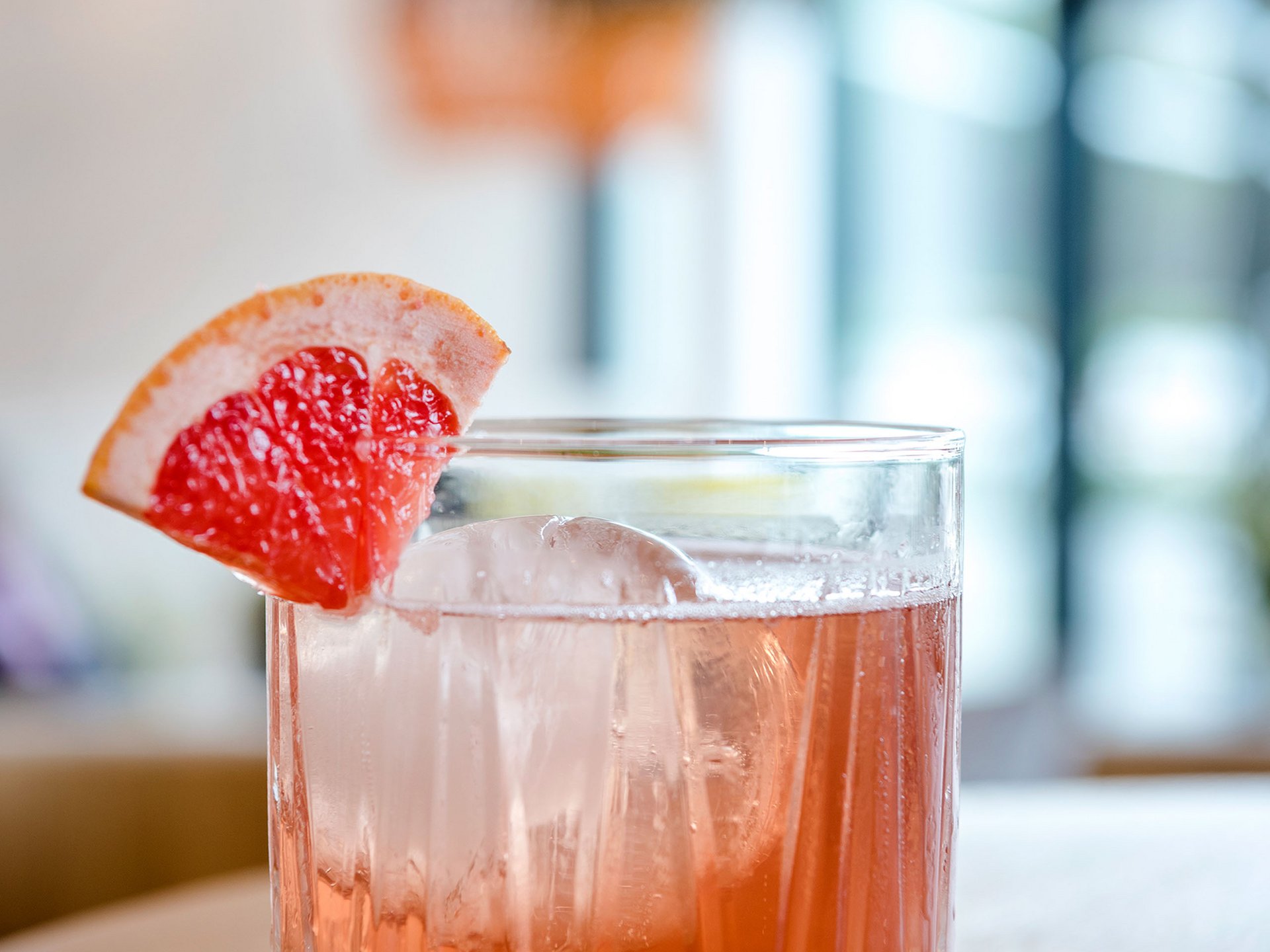 Seezeitlodge: Bildergalerie Cocktail mit Eis und Grapefruitecke auf Holzoberfläche