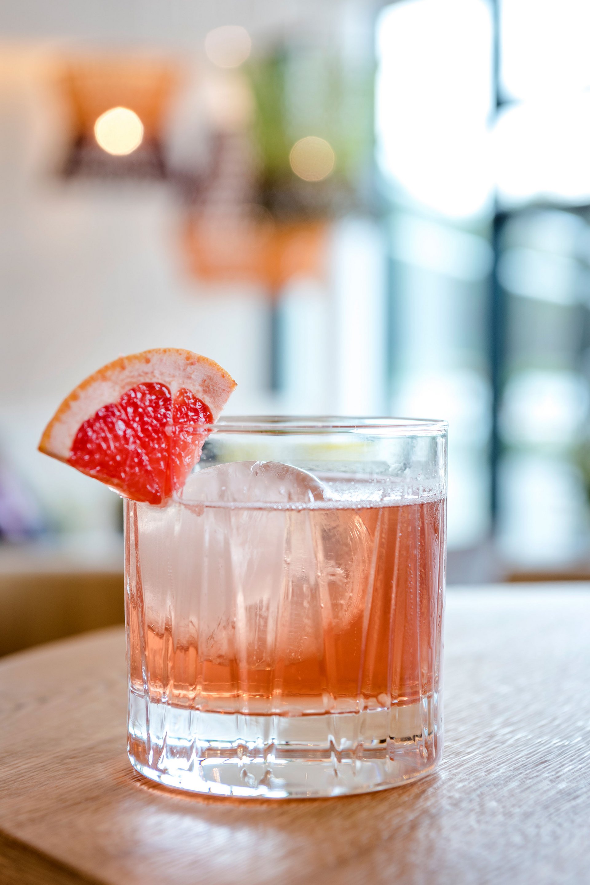 Seezeitlodge: Bildergalerie Cocktail mit Eis und Grapefruitecke auf Holzoberfläche