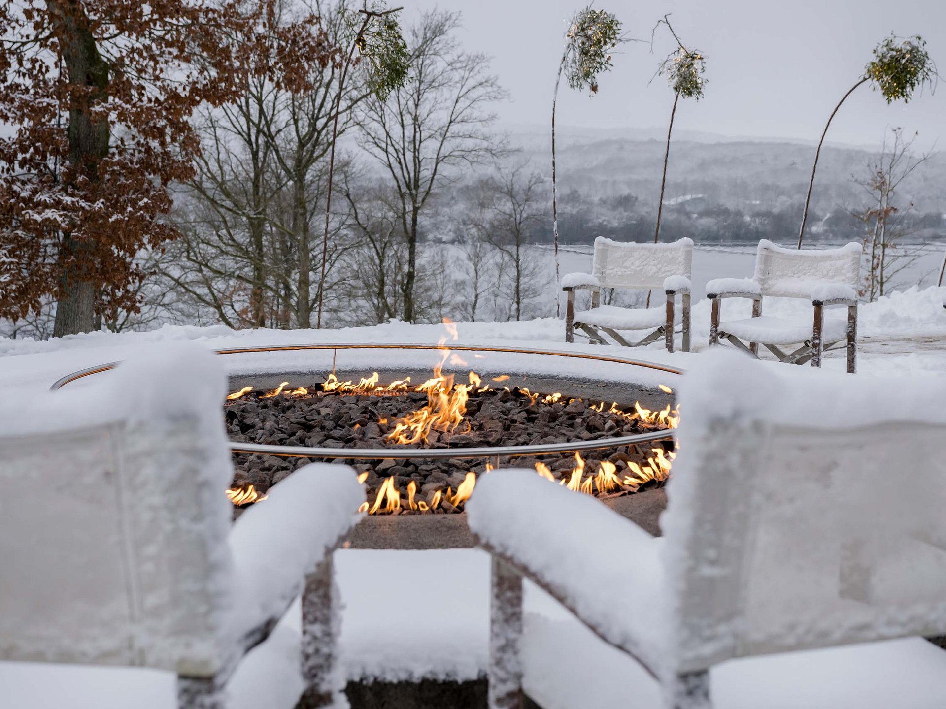 Die Seezeitlodge: Ihr Hotel am Bostalsee Schneebedeckte Sitzgruppe mit Feuerstelle und Blick auf eine winterliche Landschaft