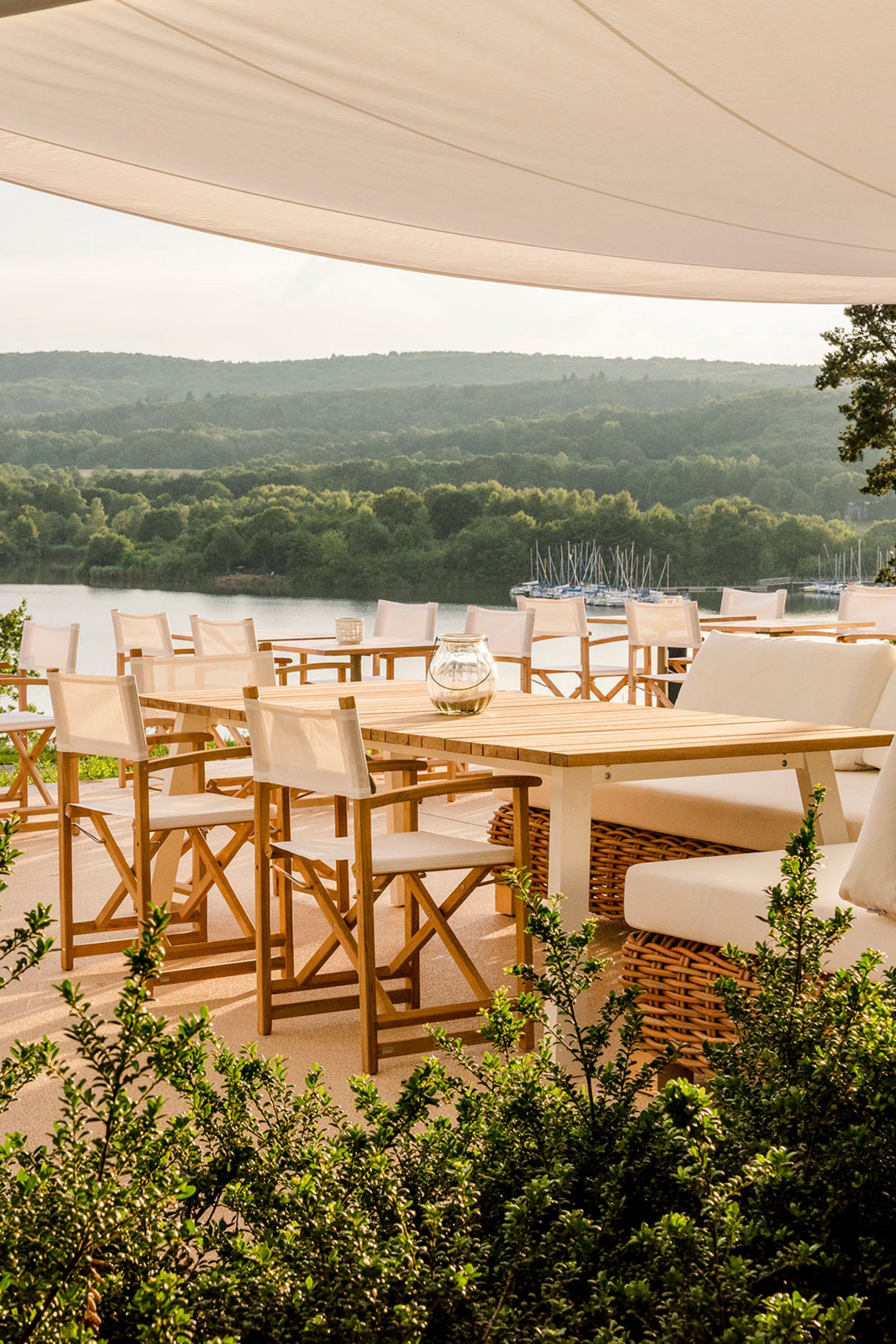 Seezeitlodge : Galerie photos Terrasse ensoleillée avec chaises blanches et vue sur le lac sous un auvent