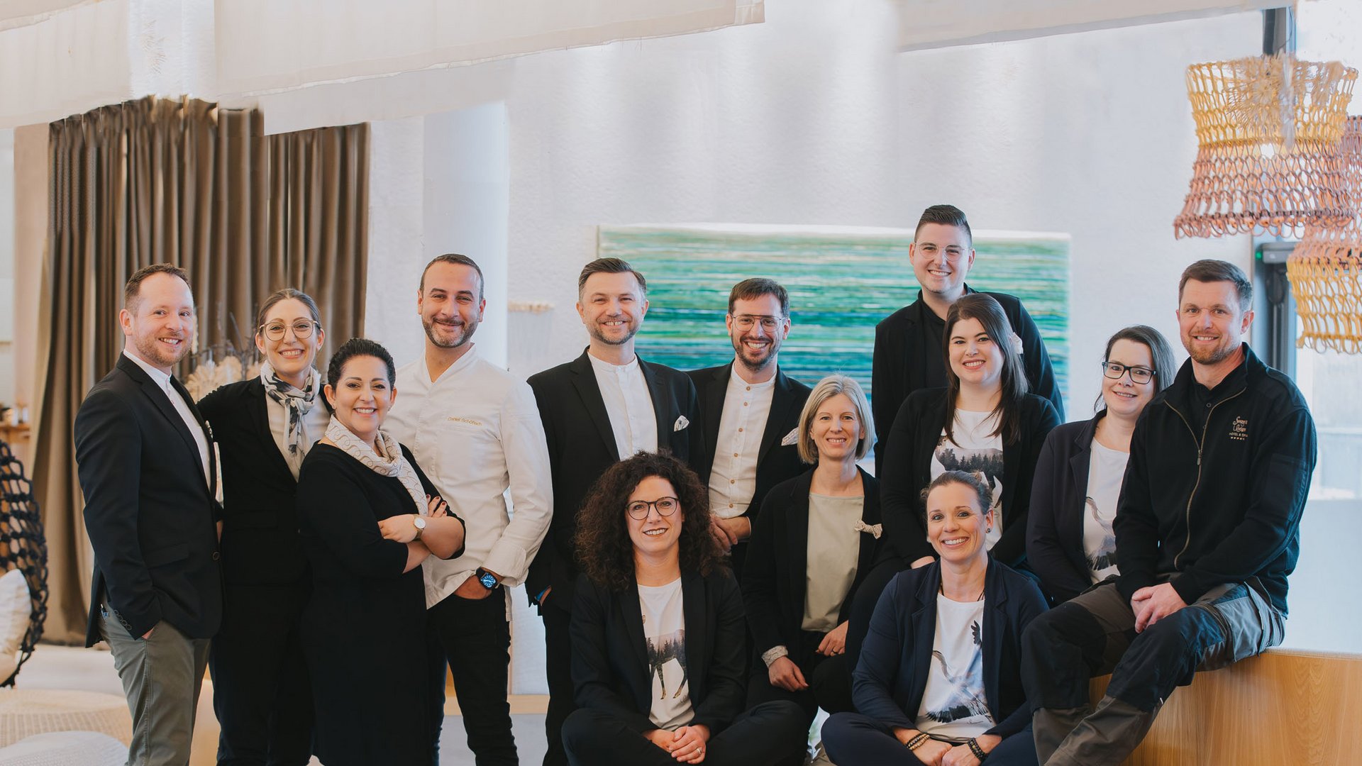 Seezeitlodge: Gastgeber mit Herz Gruppenfoto von 14 Personen in einem modernen, hellen Innenraum