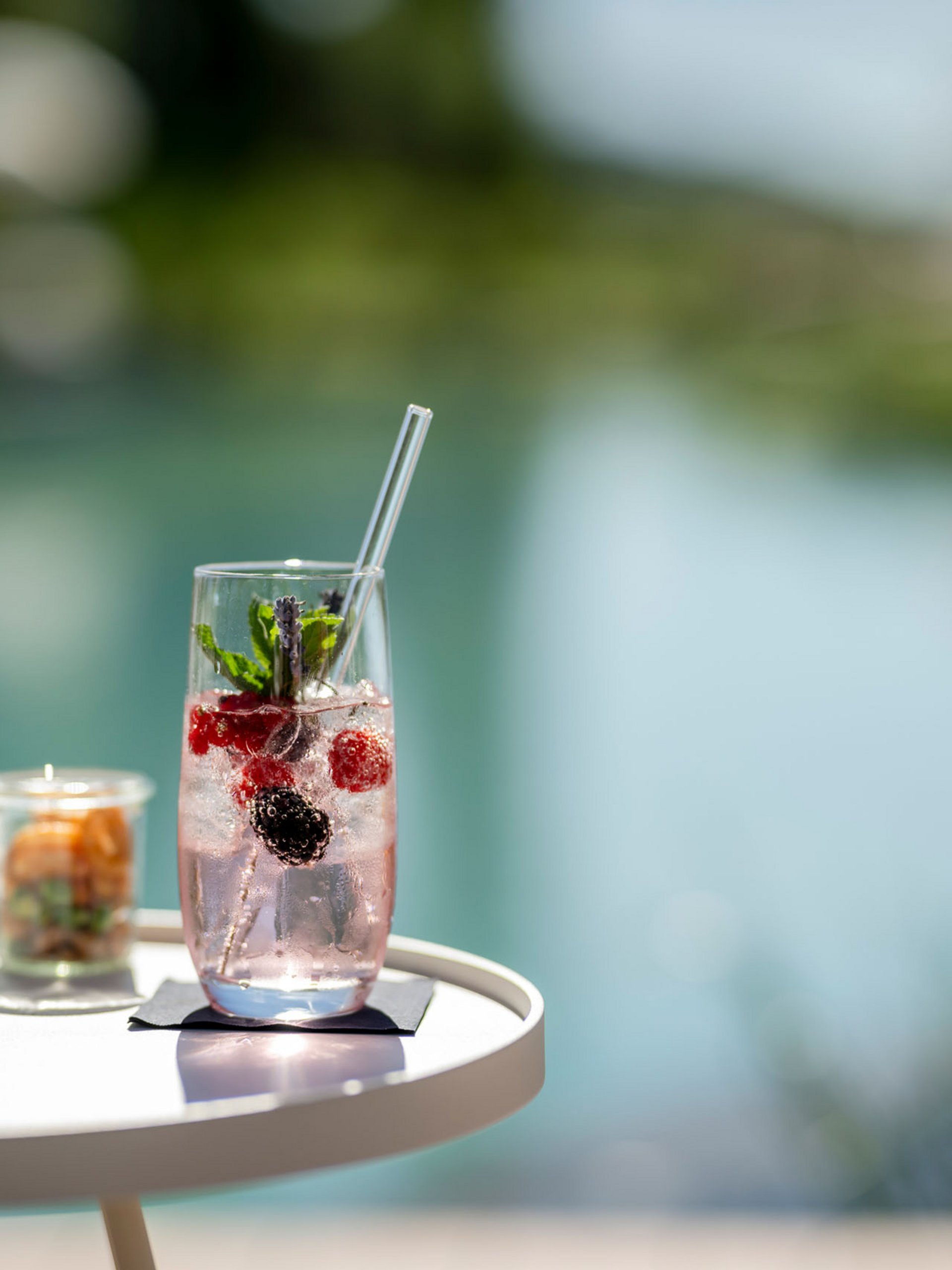 Seezeitlodge: Bildergalerie Erfrischendes Getränk mit Beeren und Minze auf einem weißen Tisch am Wasser