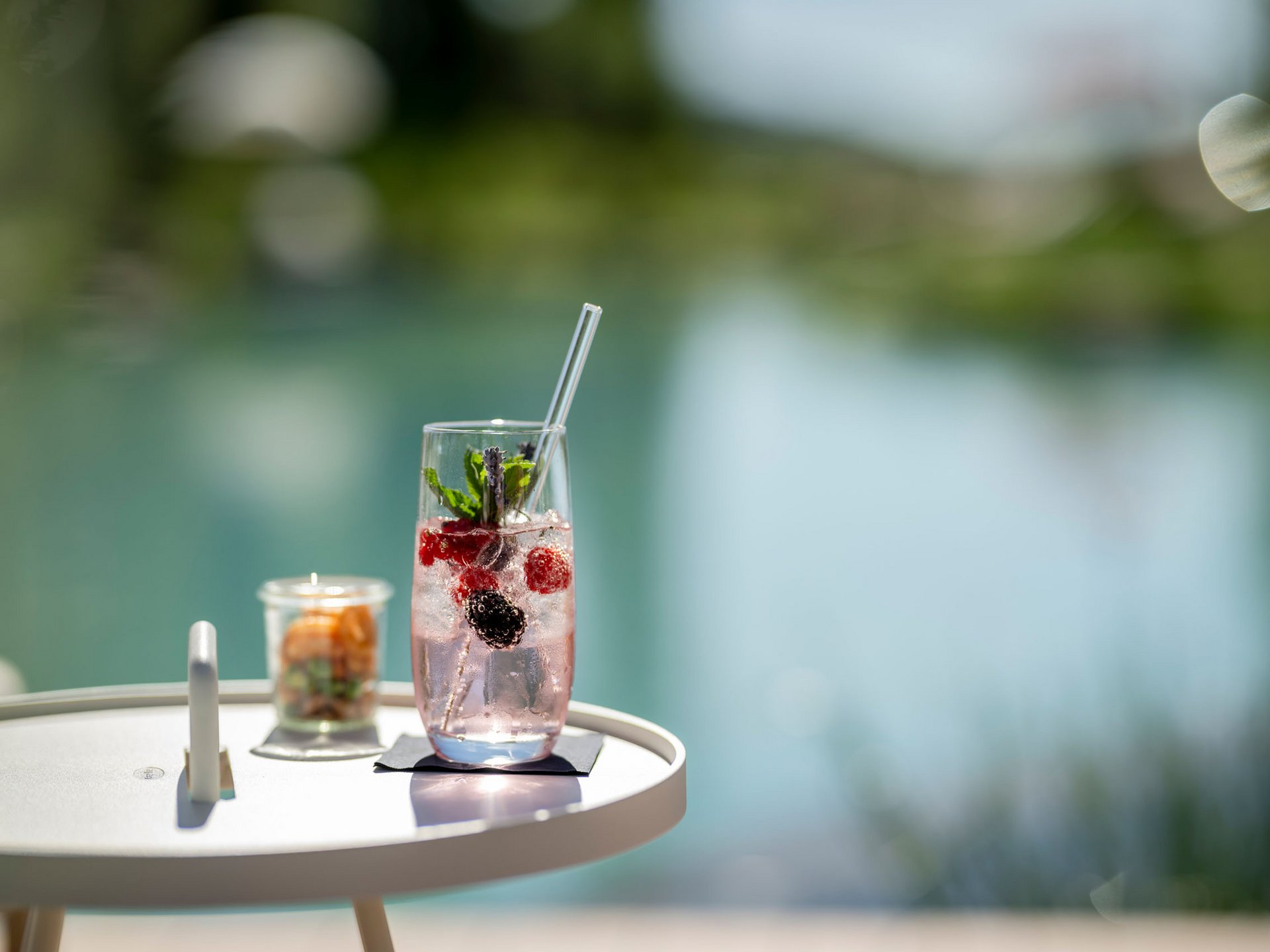 Seezeitlodge: Bildergalerie Erfrischendes Getränk mit Beeren und Minze auf einem weißen Tisch am Wasser