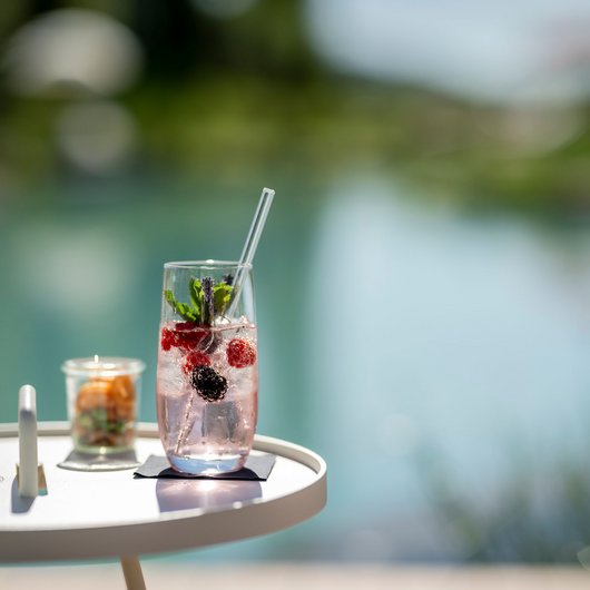 Seezeitlodge: Bar & Bistros Erfrischendes Getränk mit Beeren und Minze auf einem weißen Tisch am Wasser