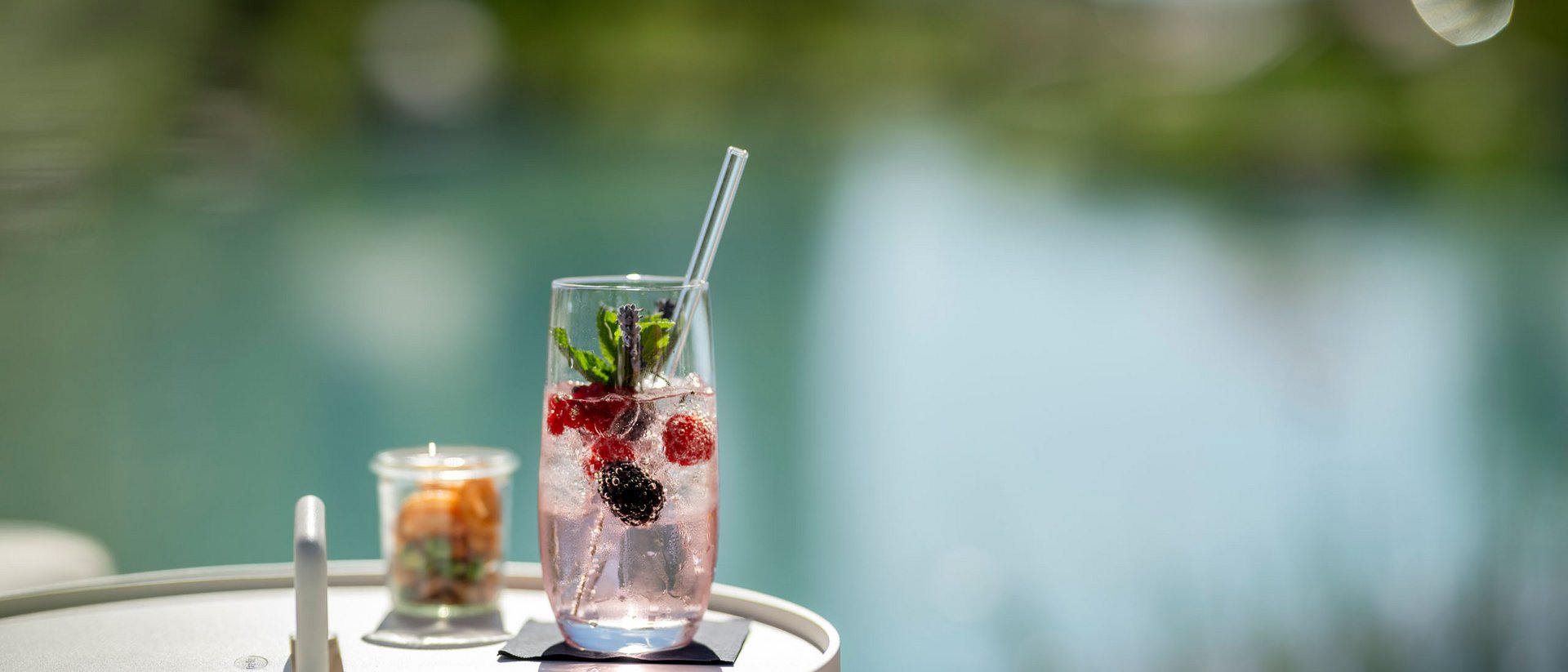 Seezeitlodge: Bildergalerie Erfrischendes Getränk mit Beeren und Minze auf einem weißen Tisch am Wasser