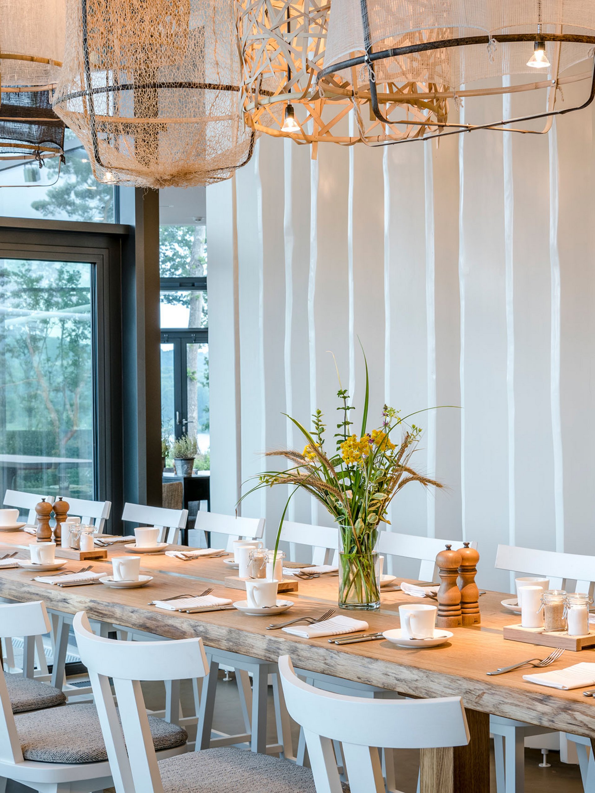 Seezeitlodge: Bildergalerie Großer Esstisch mit weißen Stühlen und modernen Lampen in einem hellen Raum