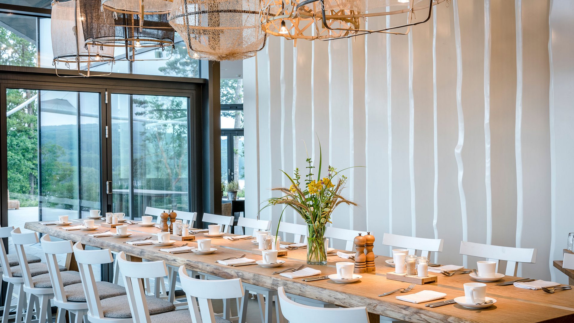 Seezeitlodge : Galerie photos Grande table à manger avec chaises blanches et luminaires modernes dans une pièce lumineuse