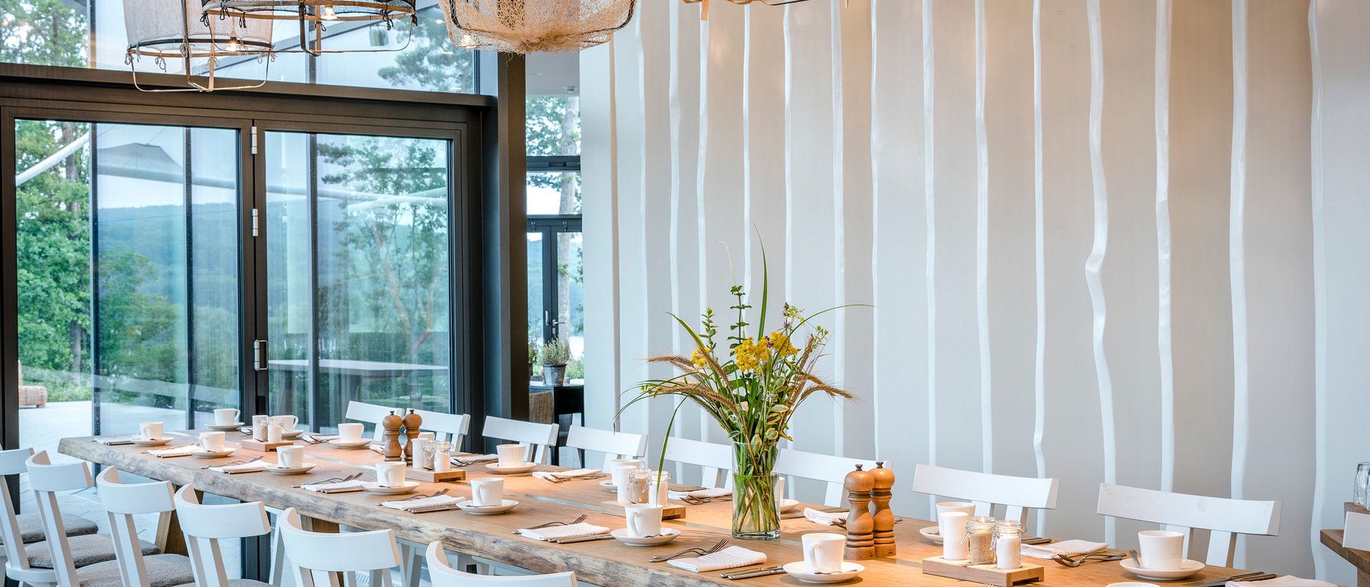 Seezeitlodge: Bildergalerie Großer Esstisch mit weißen Stühlen und modernen Lampen in einem hellen Raum