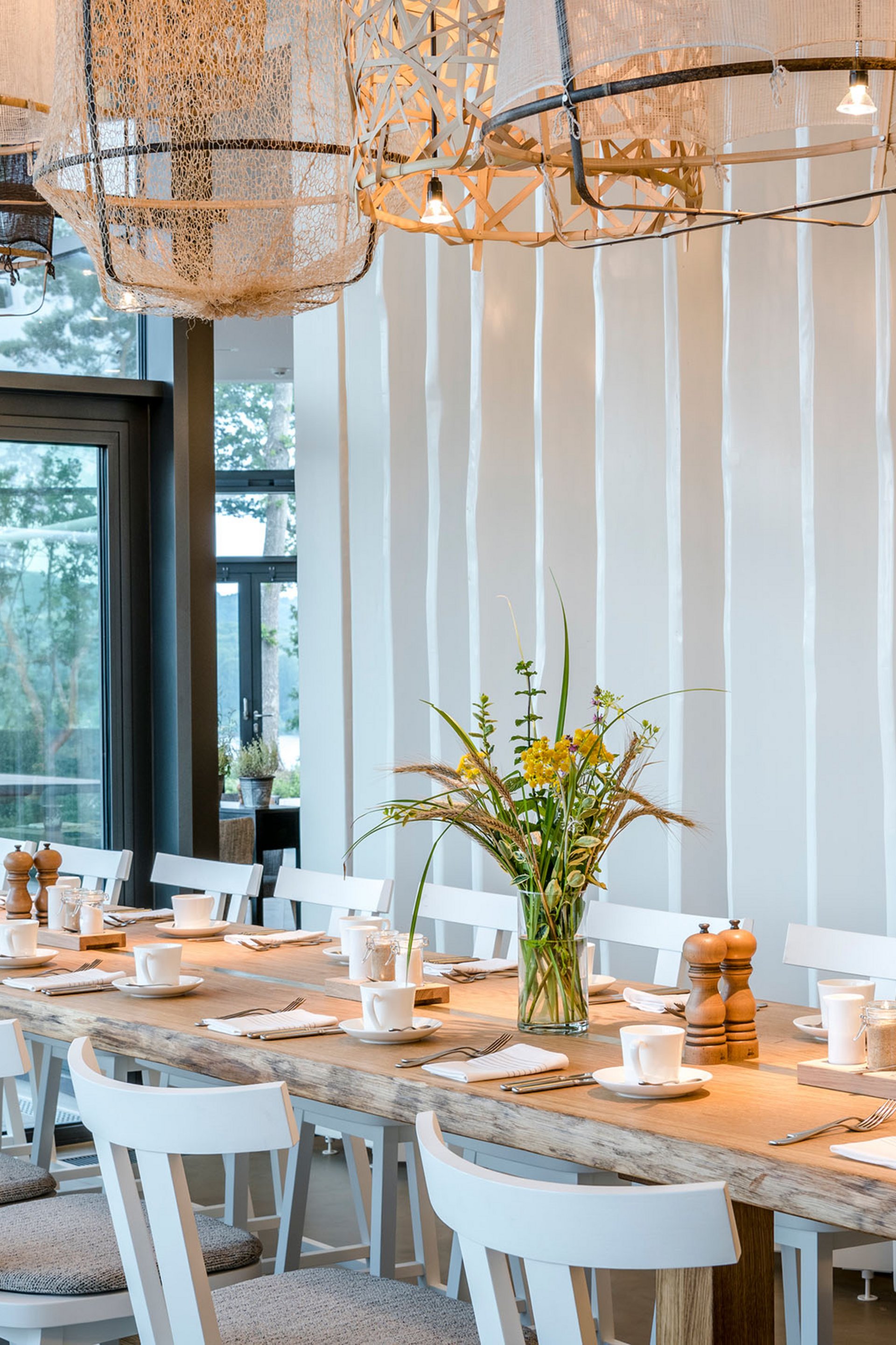 Seezeitlodge : Galerie photos Grande table à manger avec chaises blanches et luminaires modernes dans une pièce lumineuse