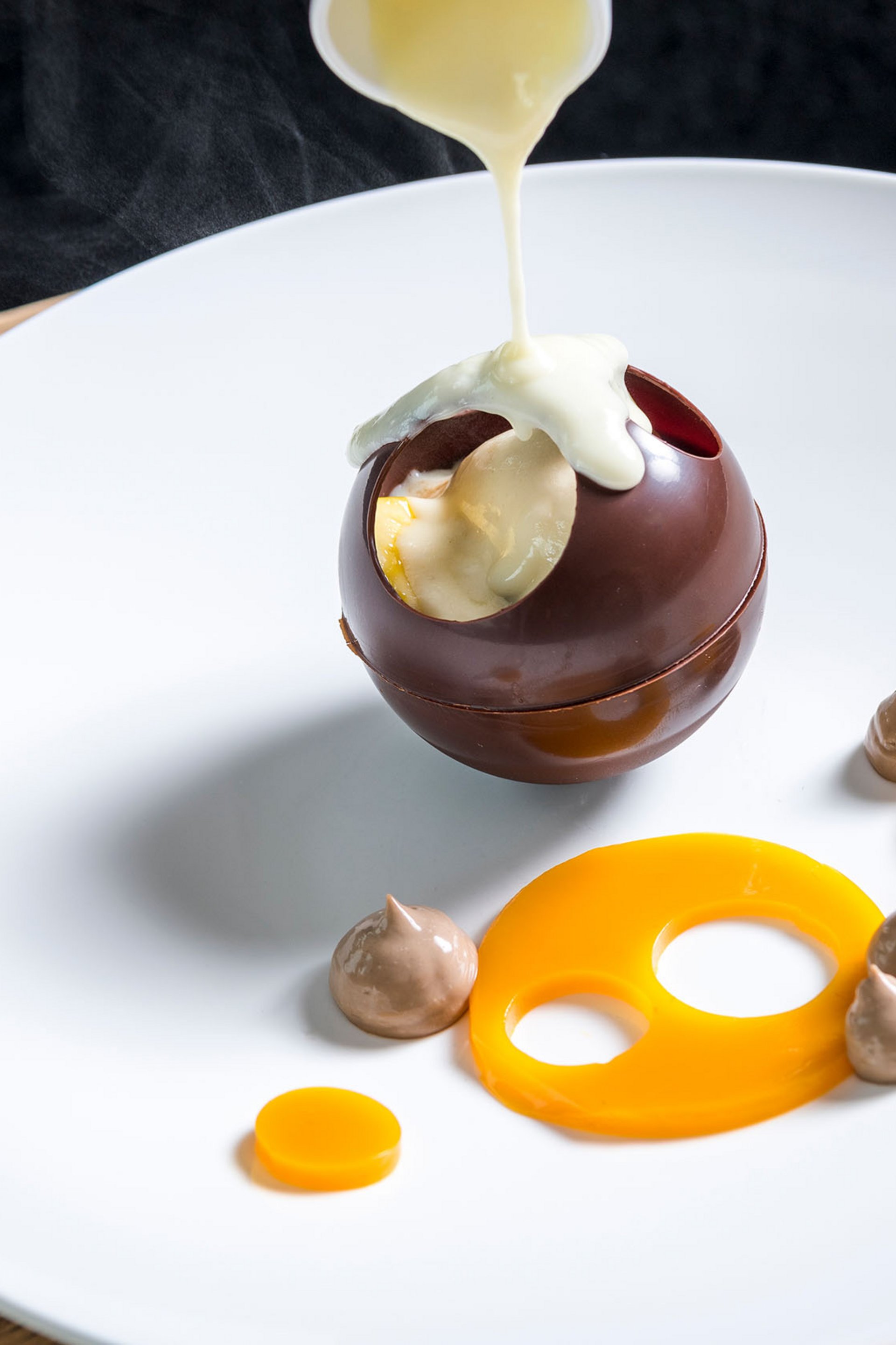 Seezeitlodge : Galerie photos Sauce chaude versée sur une sphère en chocolat creuse sur une assiette blanche