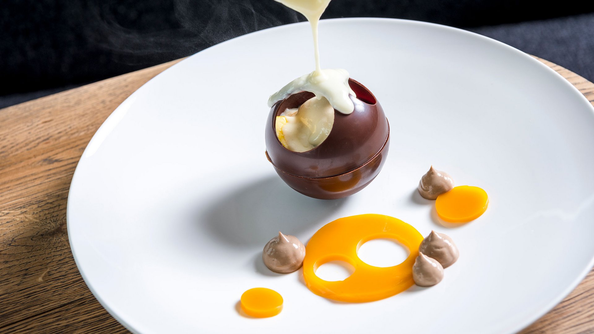 Seezeitlodge : Galerie photos Sauce chaude versée sur une sphère en chocolat creuse sur une assiette blanche