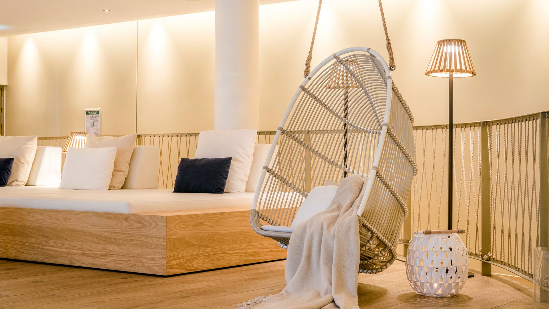 Seezeitlodge : Galerie photos Espace lounge confortable avec fauteuil suspendu, coussins et lampe sur pied