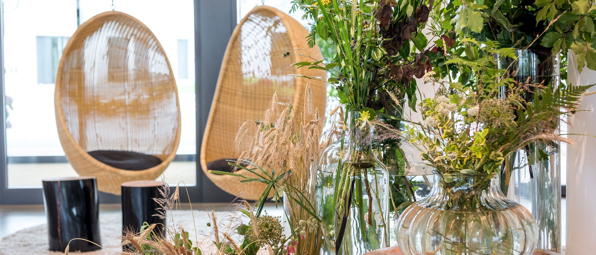 Seezeitlodge: Bildergalerie Moderner Innenraum mit Glasvasen und Pflanzen neben geflochtenen Hängestühlen
