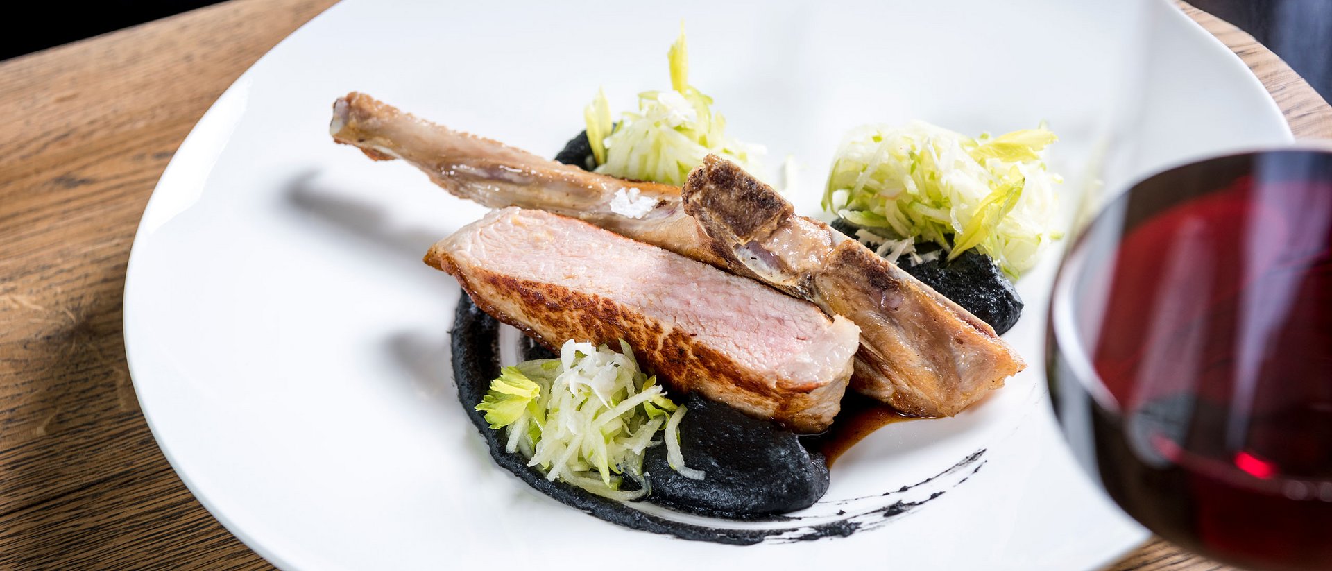 Seezeitlodge: Bildergalerie Gebratenes Lammkotelett mit schwarzer Sauce, Salat und Rotwein im Glas