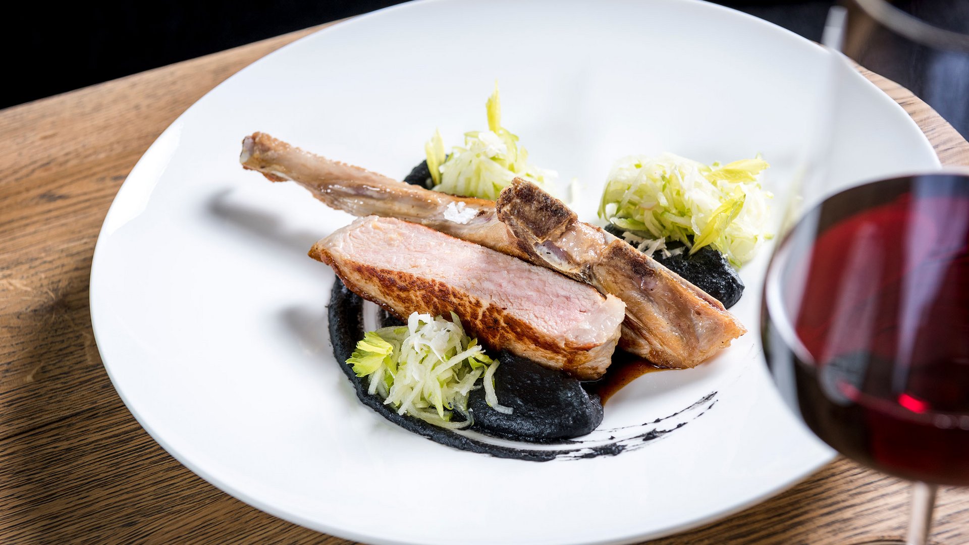 Seezeitlodge: Bildergalerie Gebratenes Lammkotelett mit schwarzer Sauce, Salat und Rotwein im Glas