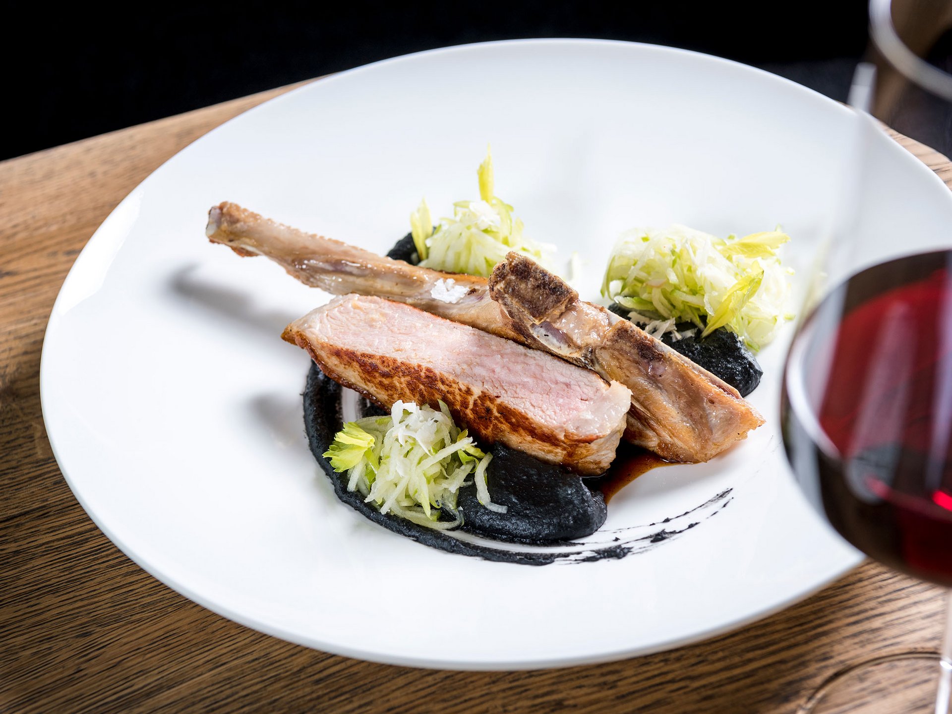 Seezeitlodge : Galerie photos Côtelette d'agneau rôtie avec sauce noire, salade et verre de vin rouge