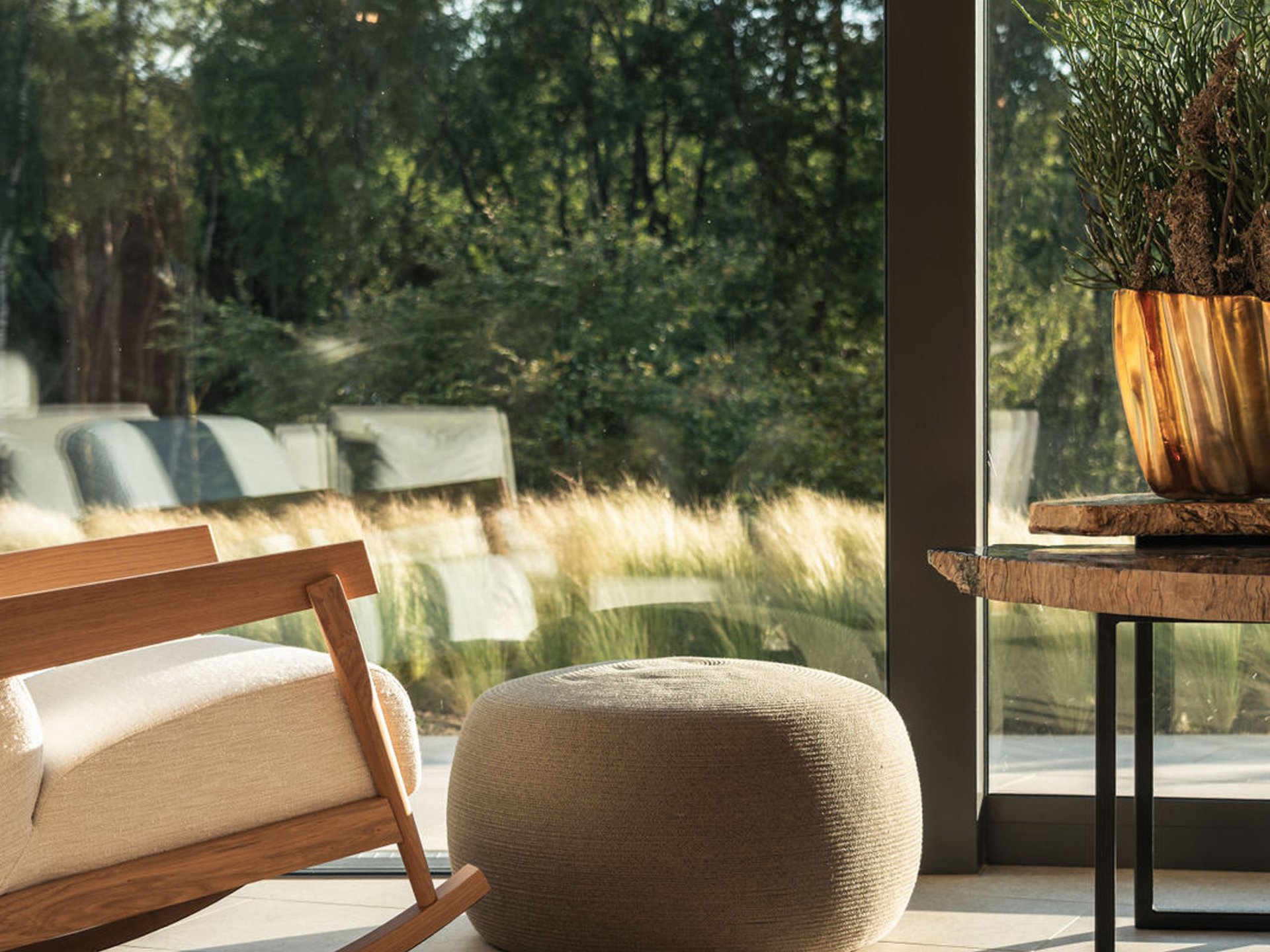 Seezeitlodge: Ihr Spa-Hotel am Bostalsee Gemütlicher Schaukelstuhl, Sitzpouf und Tisch neben großem Fenster mit Blick ins Grüne
