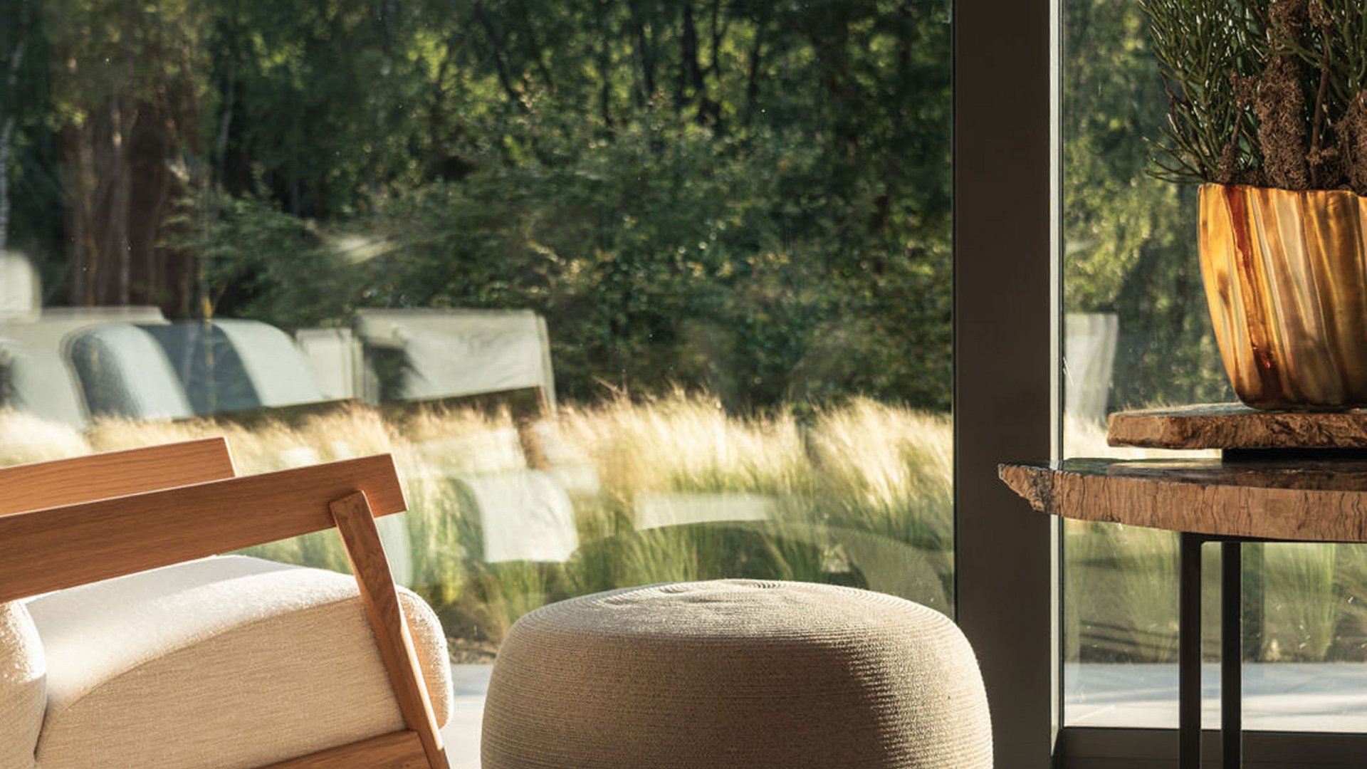 Seezeitlodge : Galerie photos Fauteuil à bascule confortable, pouf et table près d'une grande fenêtre avec vue sur la verdure