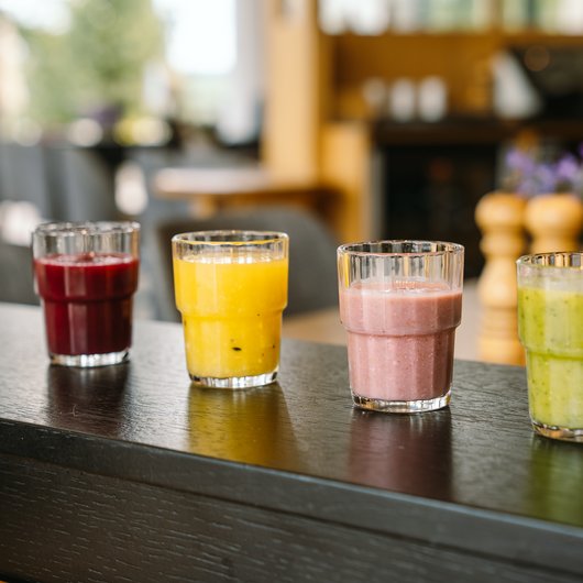 Echter Genuss am Bostalsee Vier verschiedene Smoothies in Gläsern auf einem Holztisch in einem Café