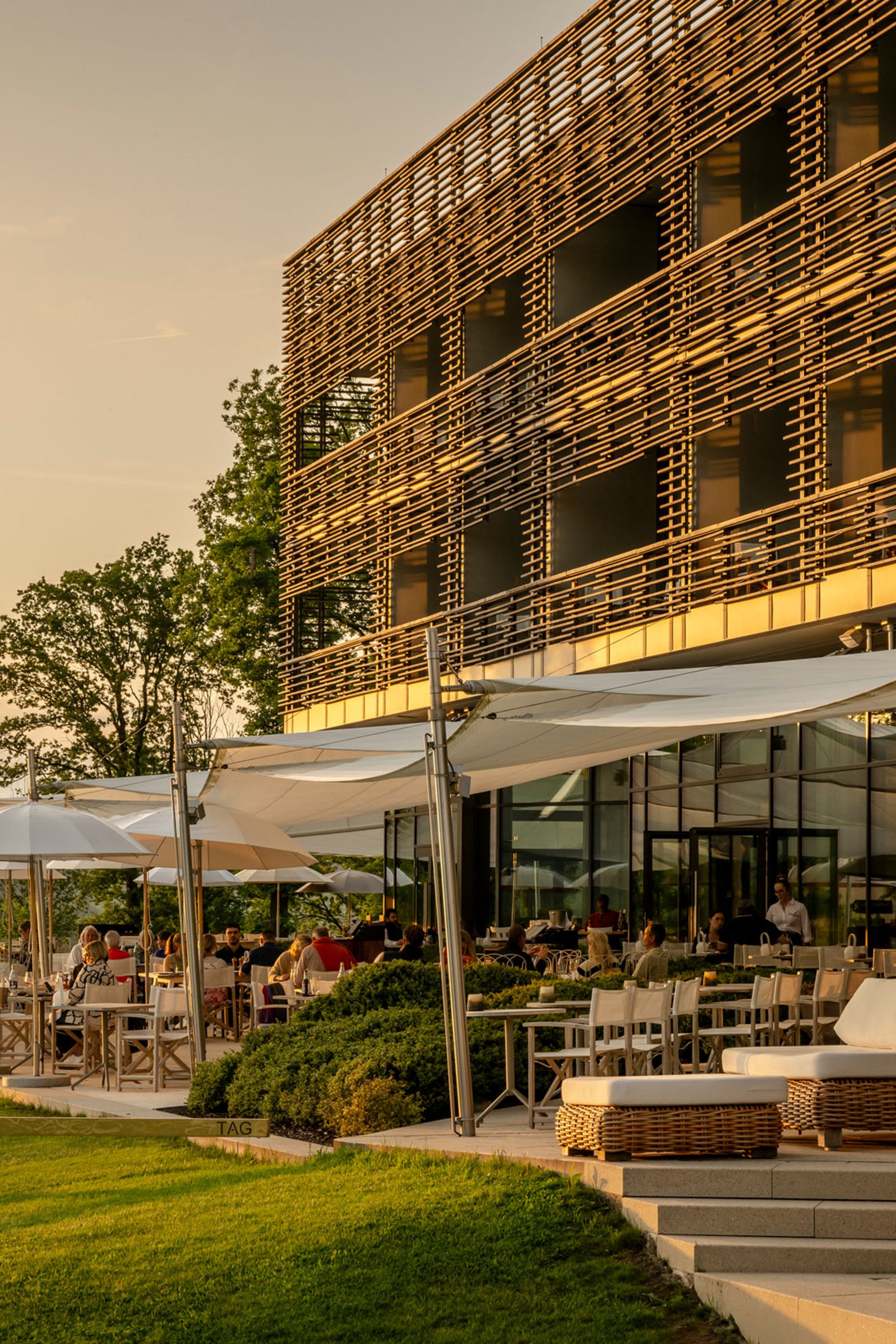Seezeitlodge : Galerie photos Terrasse ensoleillée d'un restaurant moderne avec des clients au coucher du soleil