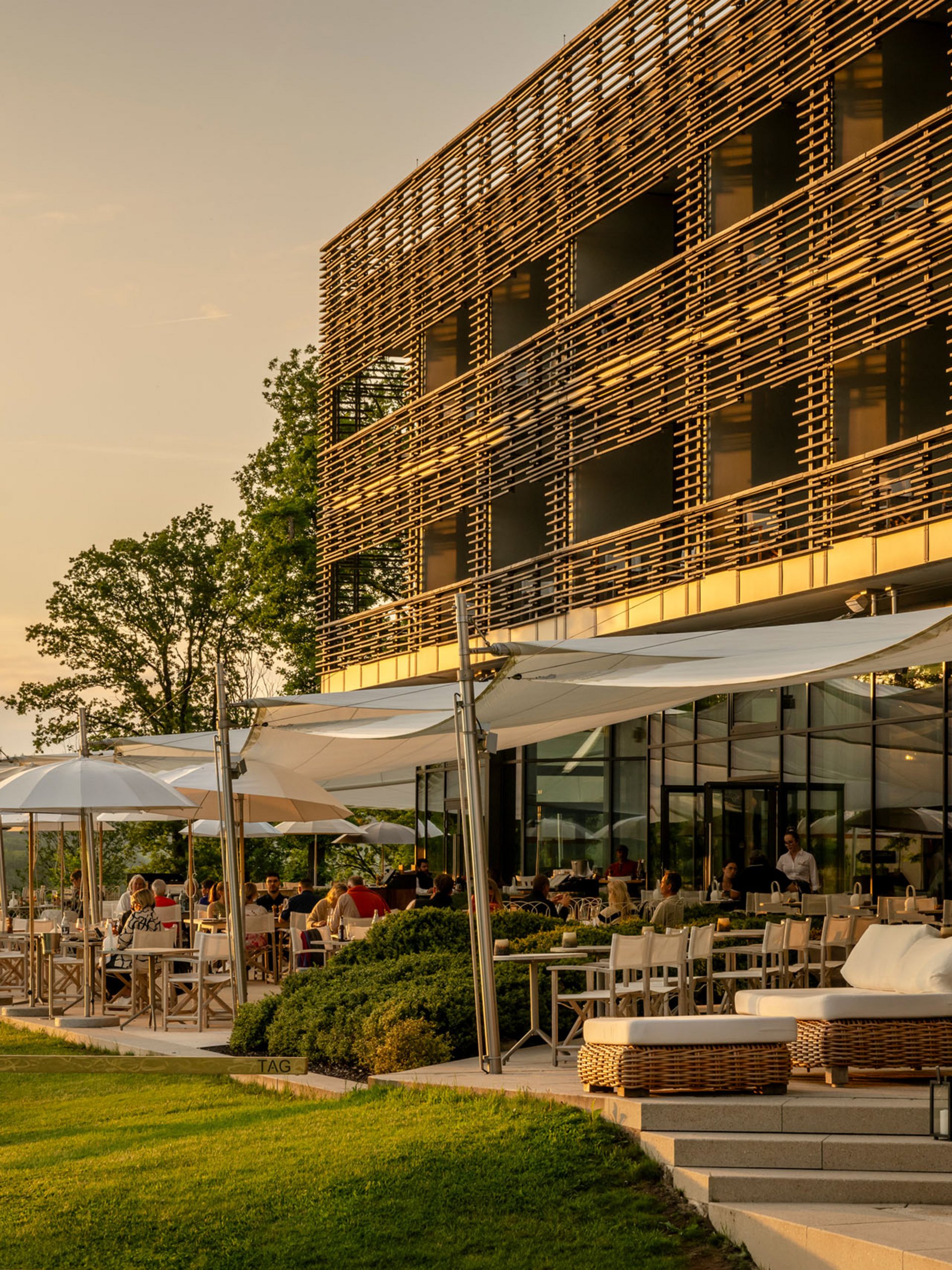 Seezeitlodge : Galerie photos Terrasse ensoleillée d'un restaurant moderne avec des clients au coucher du soleil