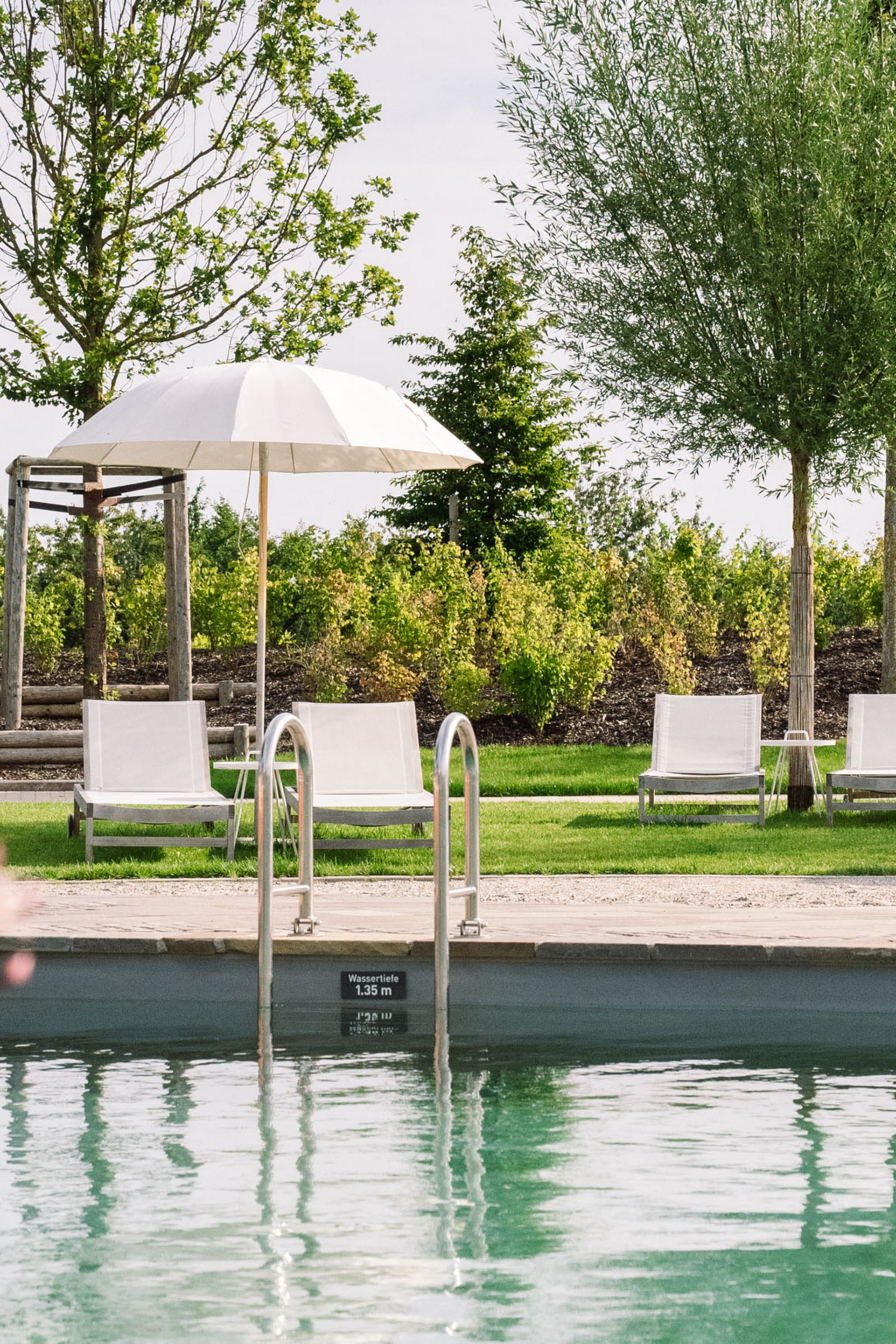 Seezeitlodge : Galerie photos Piscine avec chaises longues et parasols dans un jardin verdoyant