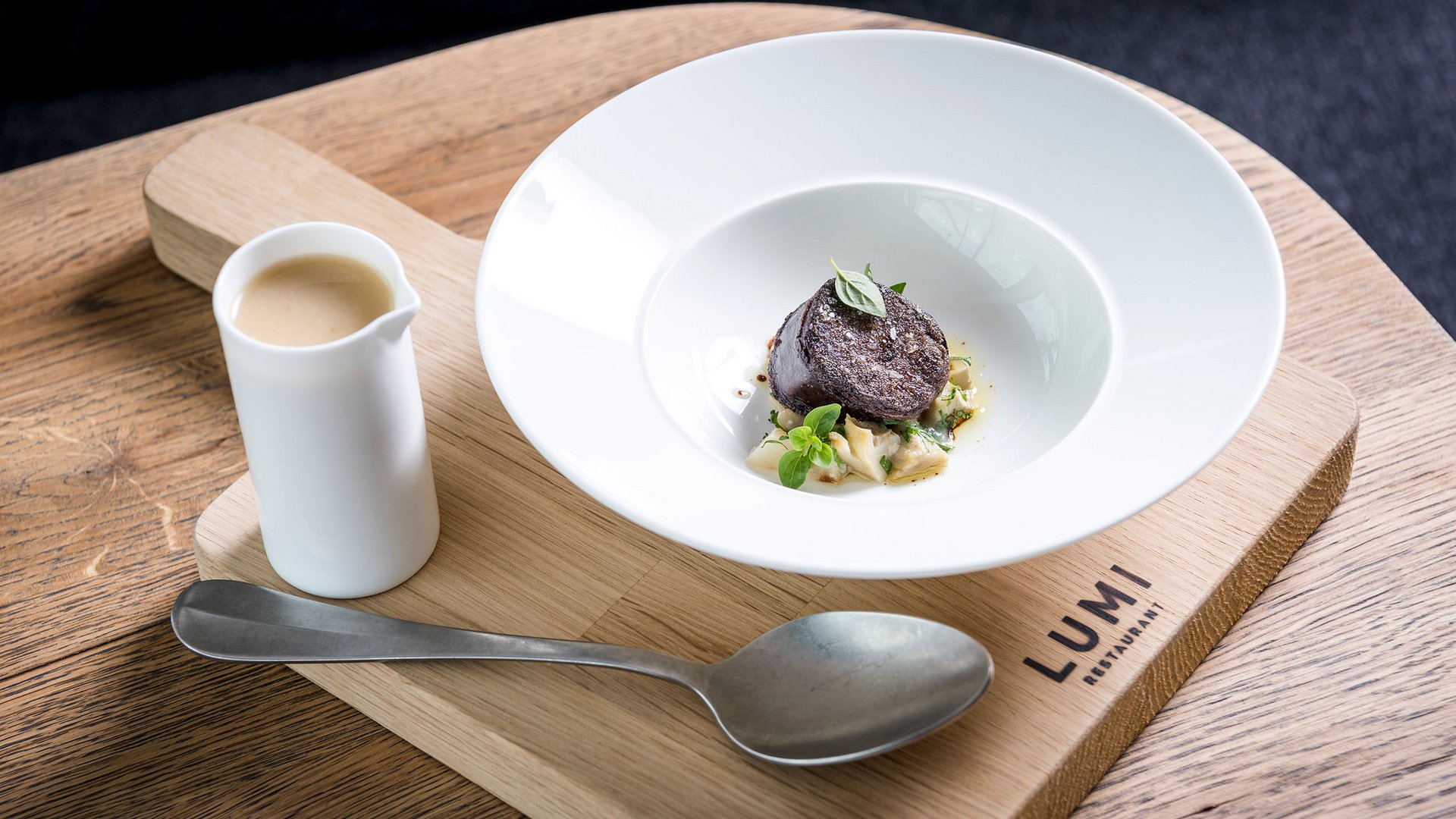 Seezeitlodge: Bildergalerie Fein angerichtete Gourmet-Speise mit Sauce, serviert auf Holzbrett im Lumi Restaurant