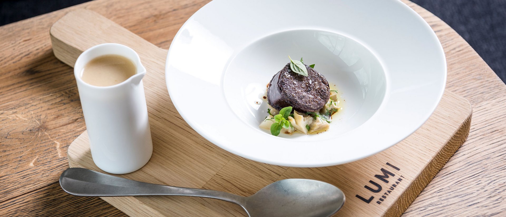 Seezeitlodge : Galerie photos Plat gastronomique élégant avec sauce sur planche en bois au restaurant Lumi