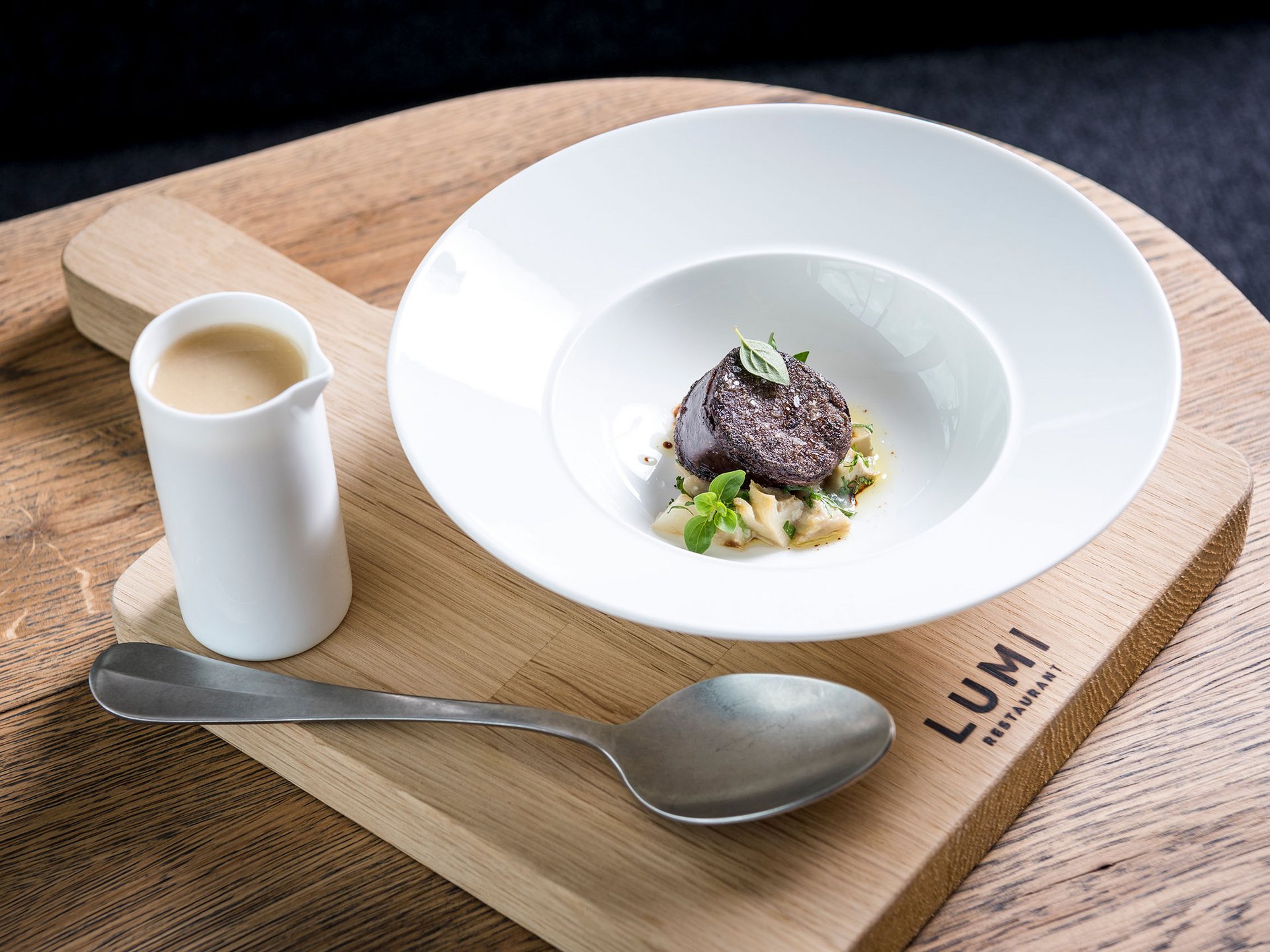 Seezeitlodge: Bildergalerie Fein angerichtete Gourmet-Speise mit Sauce, serviert auf Holzbrett im Lumi Restaurant