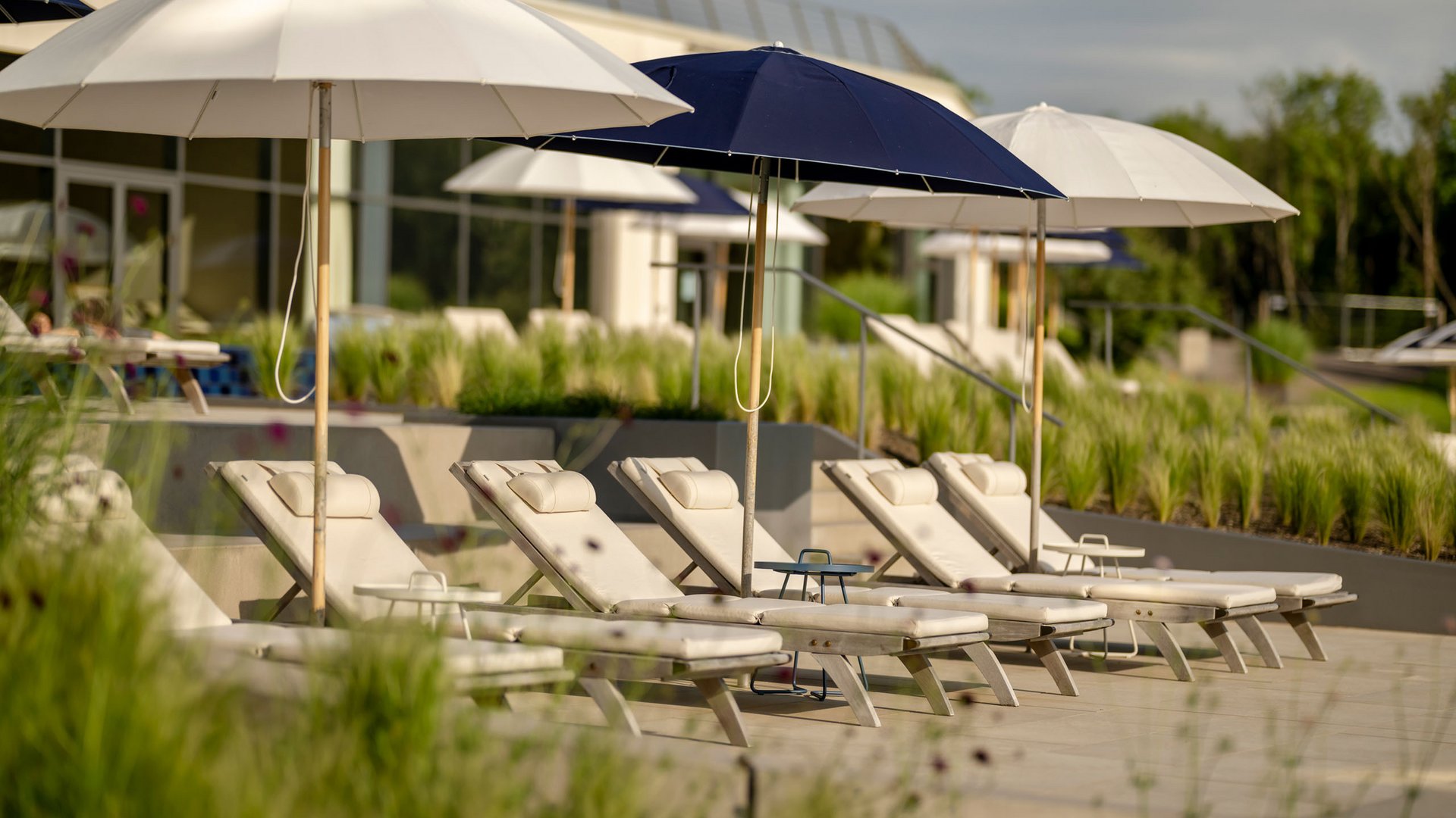 Seezeitlodge : Galerie photos Chaises longues vides avec parasols dans une zone de piscine ensoleillée