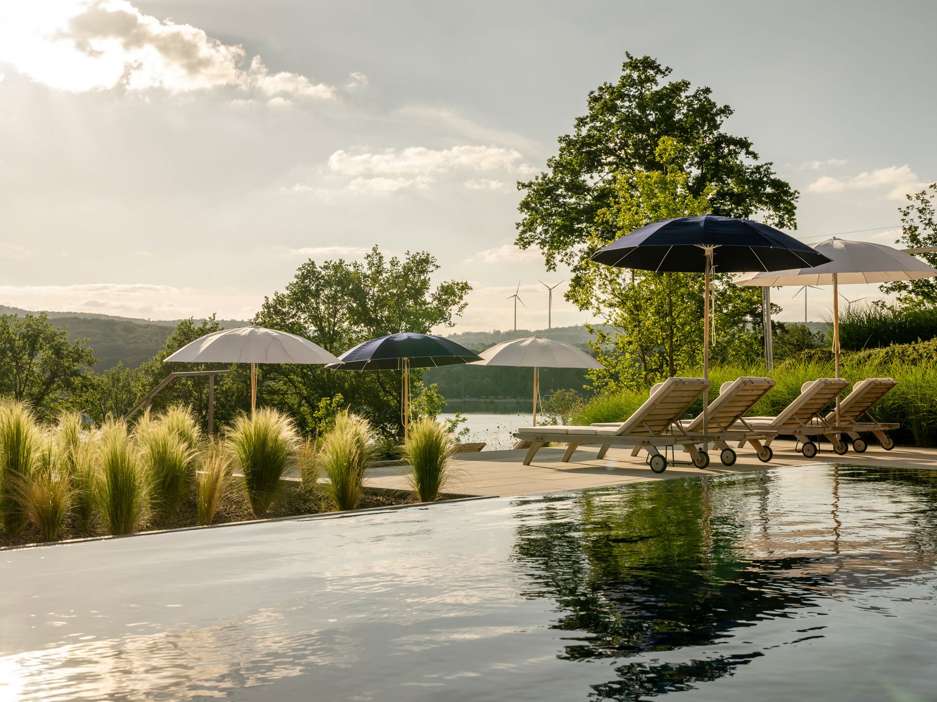 Seezeitlodge: Bildergalerie Pool mit Liegestühlen und Sonnenschirmen in natürlicher Landschaft bei Sonnenlicht