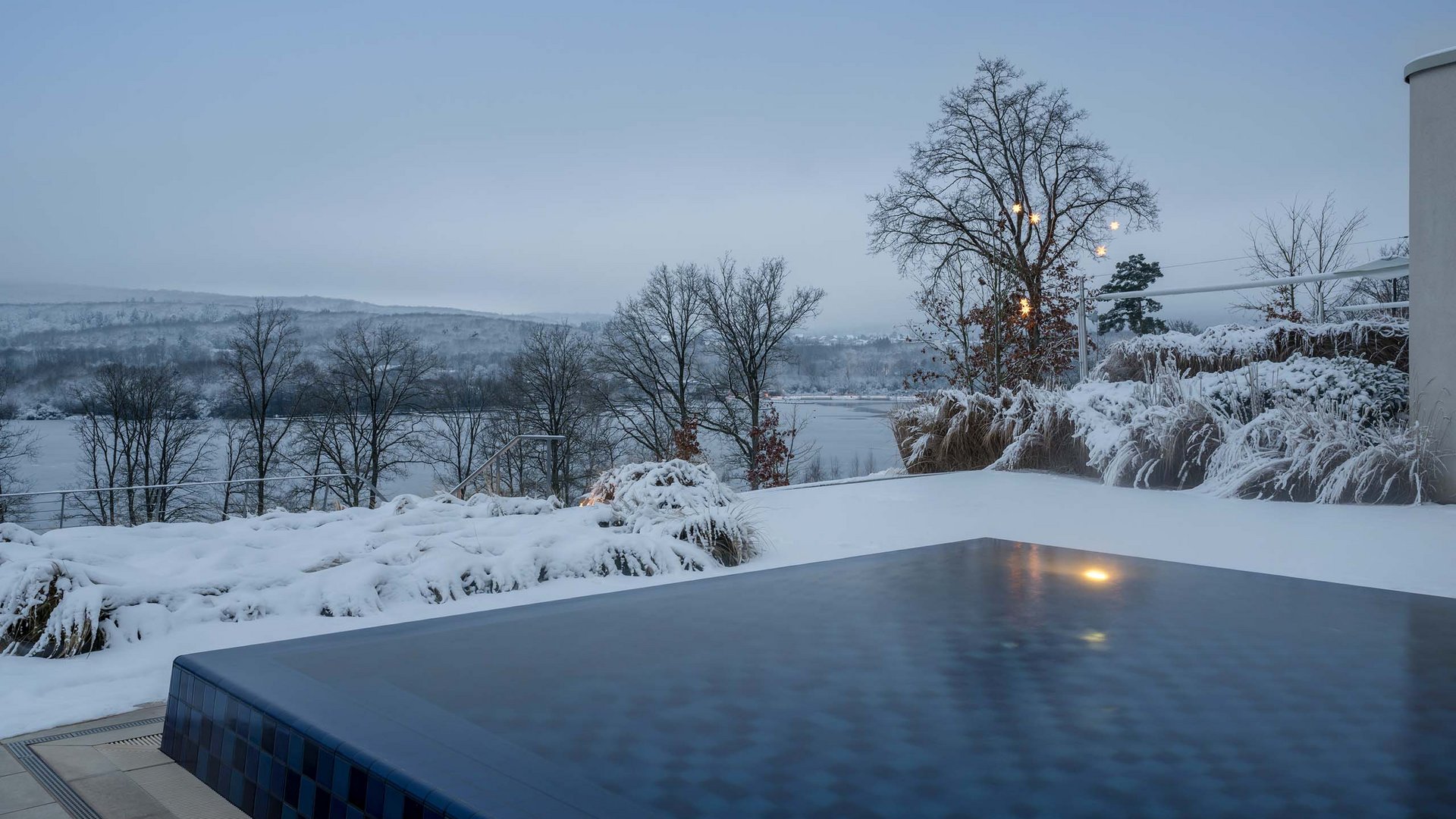Die Seezeitlodge: Ihr Hotel am Bostalsee Außenpool im Schnee mit Blick auf verschneite Bäume und Hügel in der Dämmerung