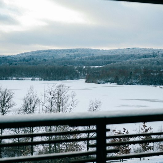 Die Seezeitlodge: Ihr Hotel am Bostalsee Verschneite Landschaft mit zugefrorenem See, gesehen durch ein Balkongeländer