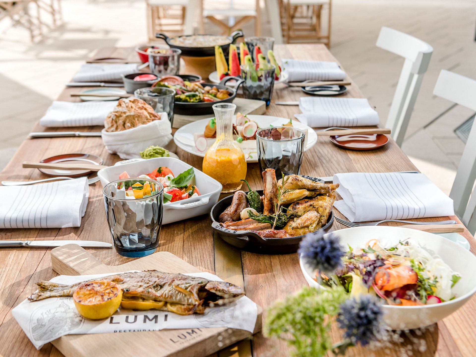 Seezeitlodge: Bildergalerie Essensauswahl auf einem Holztisch mit gebratenem Fisch, Fleisch und Salaten