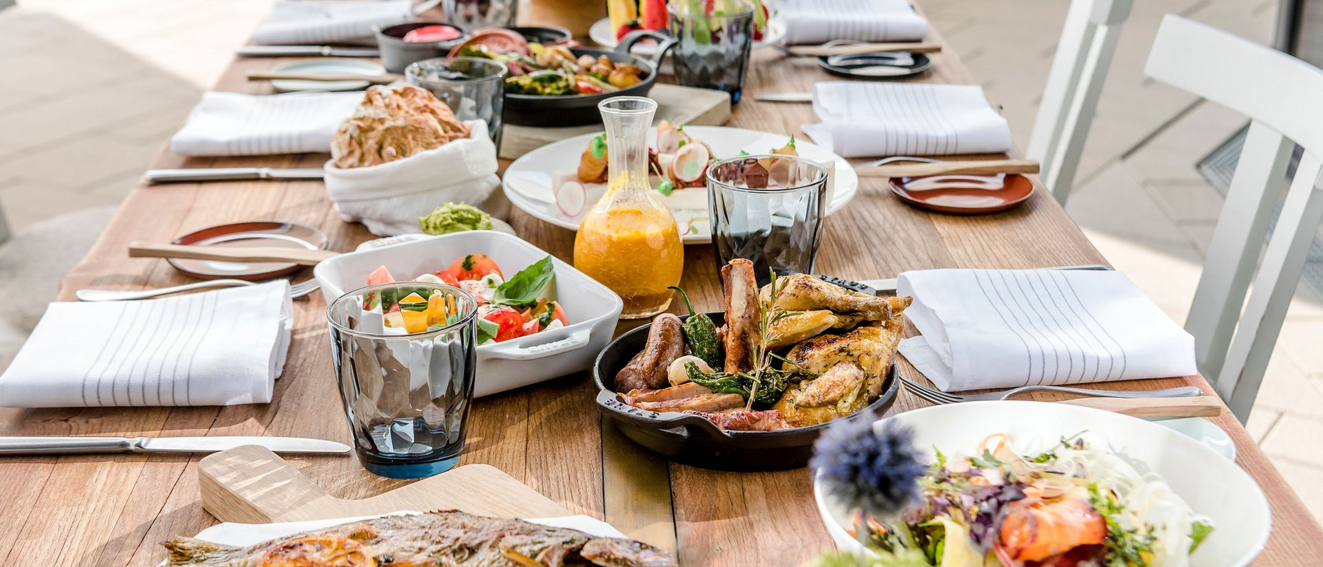 Seezeitlodge: Bildergalerie Essensauswahl auf einem Holztisch mit gebratenem Fisch, Fleisch und Salaten