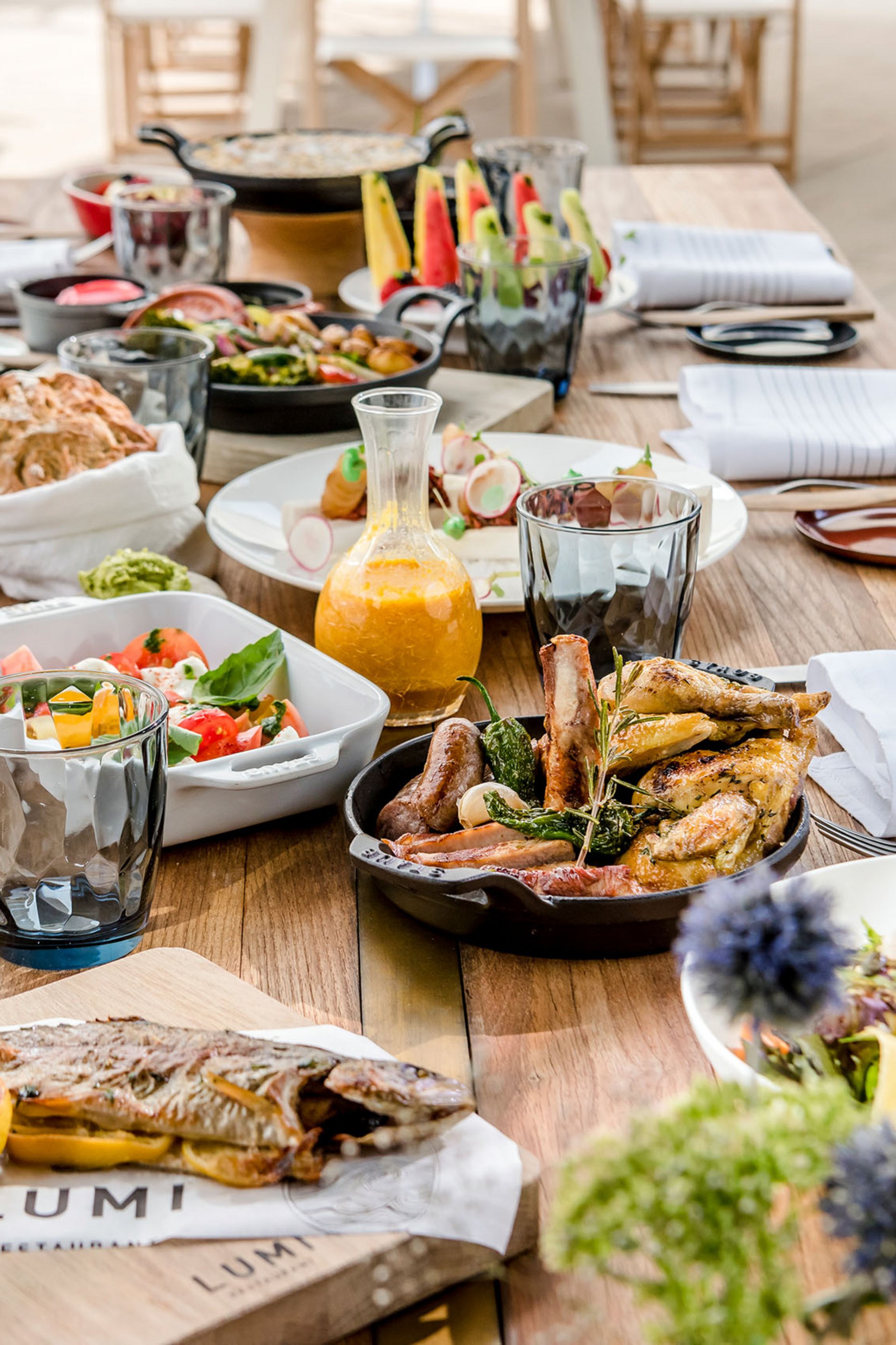 Seezeitlodge: Bildergalerie Essensauswahl auf einem Holztisch mit gebratenem Fisch, Fleisch und Salaten