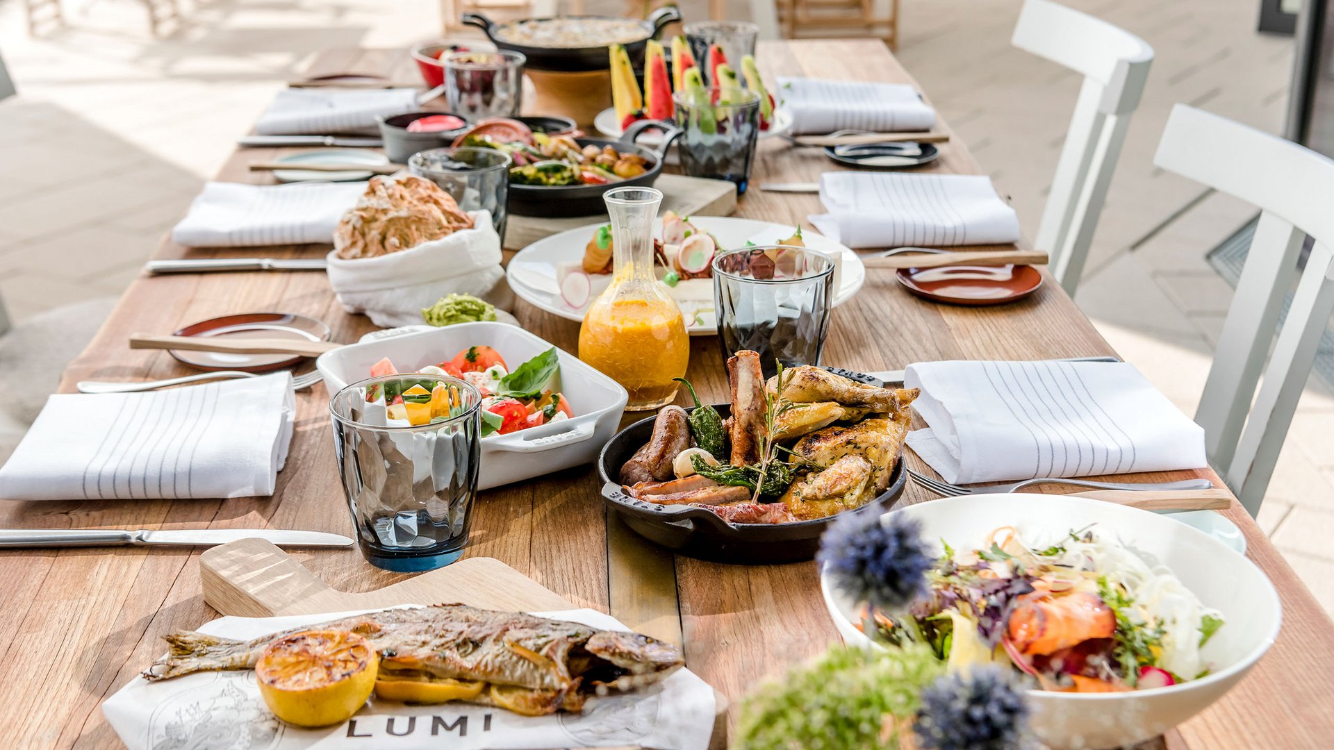 Seezeitlodge : Galerie photos Table en bois dressée avec poisson grillé, viande et salades variées