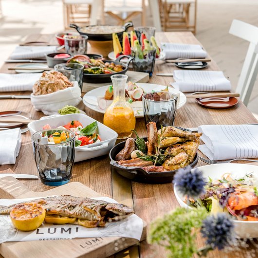 Ihr Genusshotel am Bostalsee Essensauswahl auf einem Holztisch mit gebratenem Fisch, Fleisch und Salaten