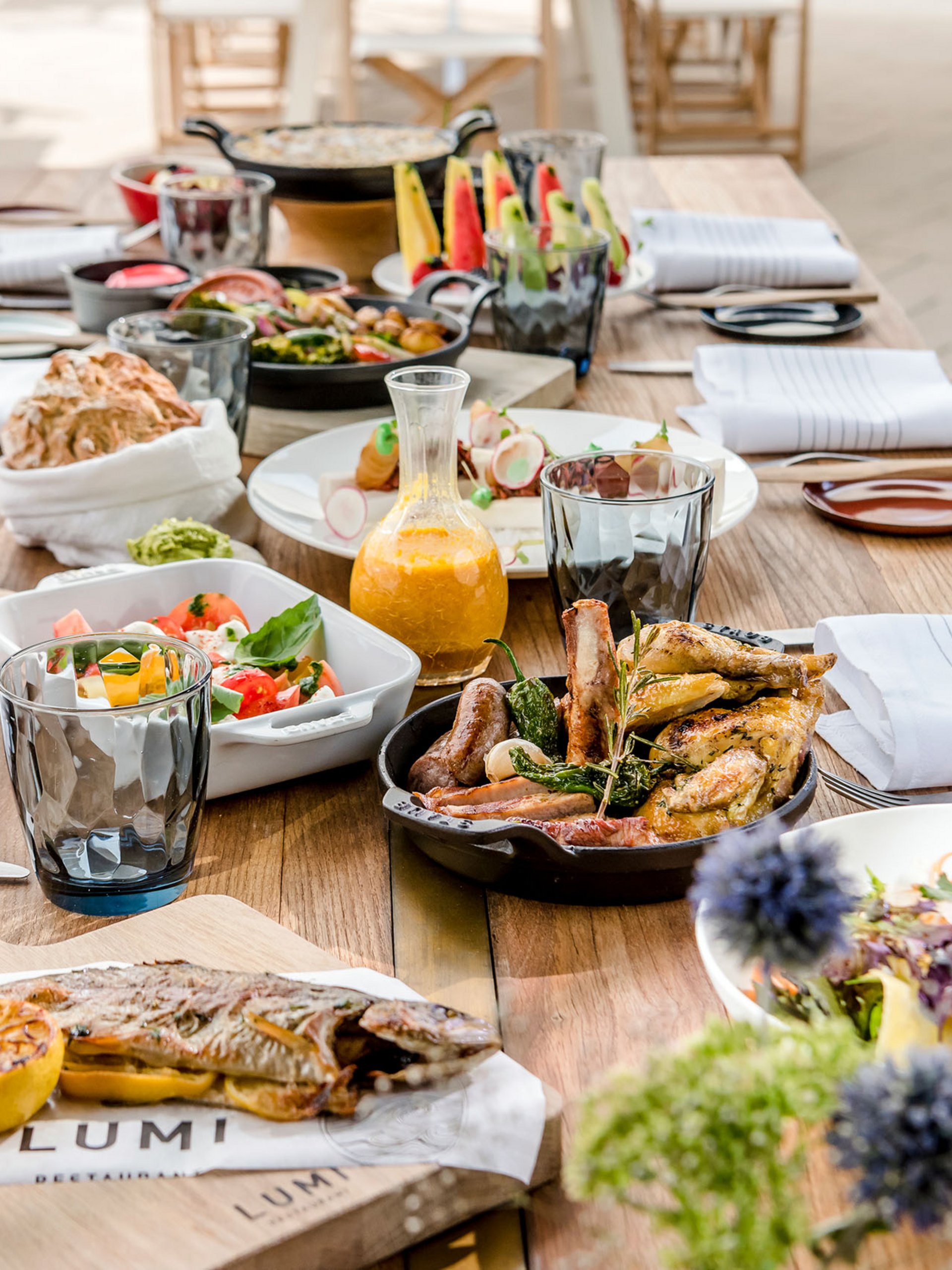 Seezeitlodge : Galerie photos Table en bois dressée avec poisson grillé, viande et salades variées