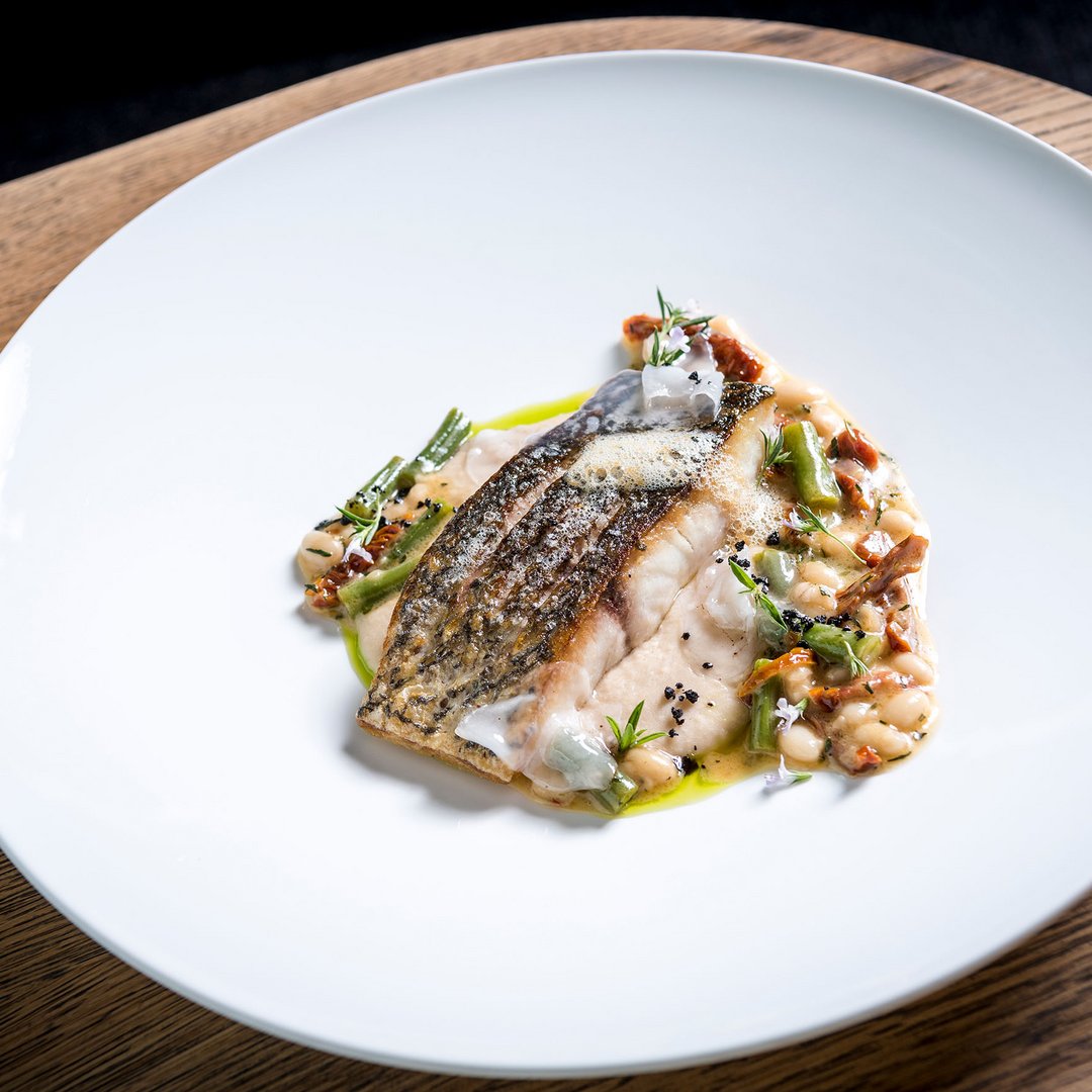 Seezeitlodge : protection des données Filet de poisson grillé avec haricots blancs et légumes dans une assiette blanche