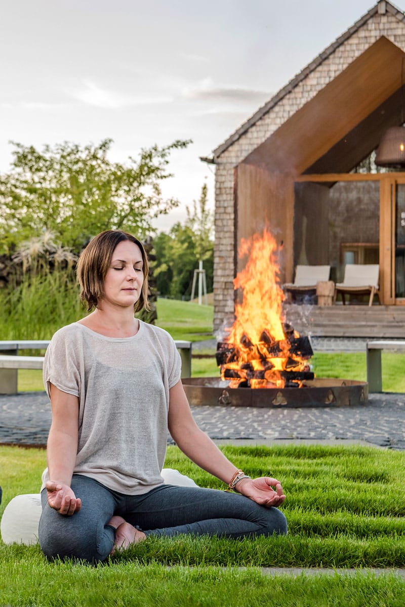 Stefanie Dell meditieren vor der Feuerstelle - Seezeitlodge Hotel & Spa